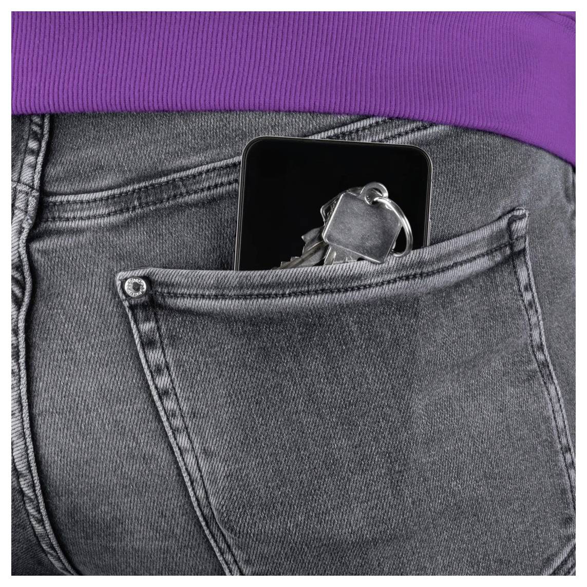 Die Hintertasche einer grauen Jeans hält ein Smartphone, mit Schlüsseln, die dahinter unter einem violetten Hemd verstaut sind.