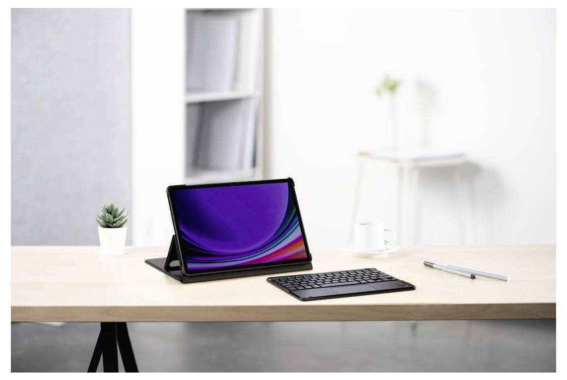 Tablet mit Tastatur auf einem ordentlichen Schreibtisch, daneben ein Stift und eine kleine Pflanze in einer hellen Büroumgebung.