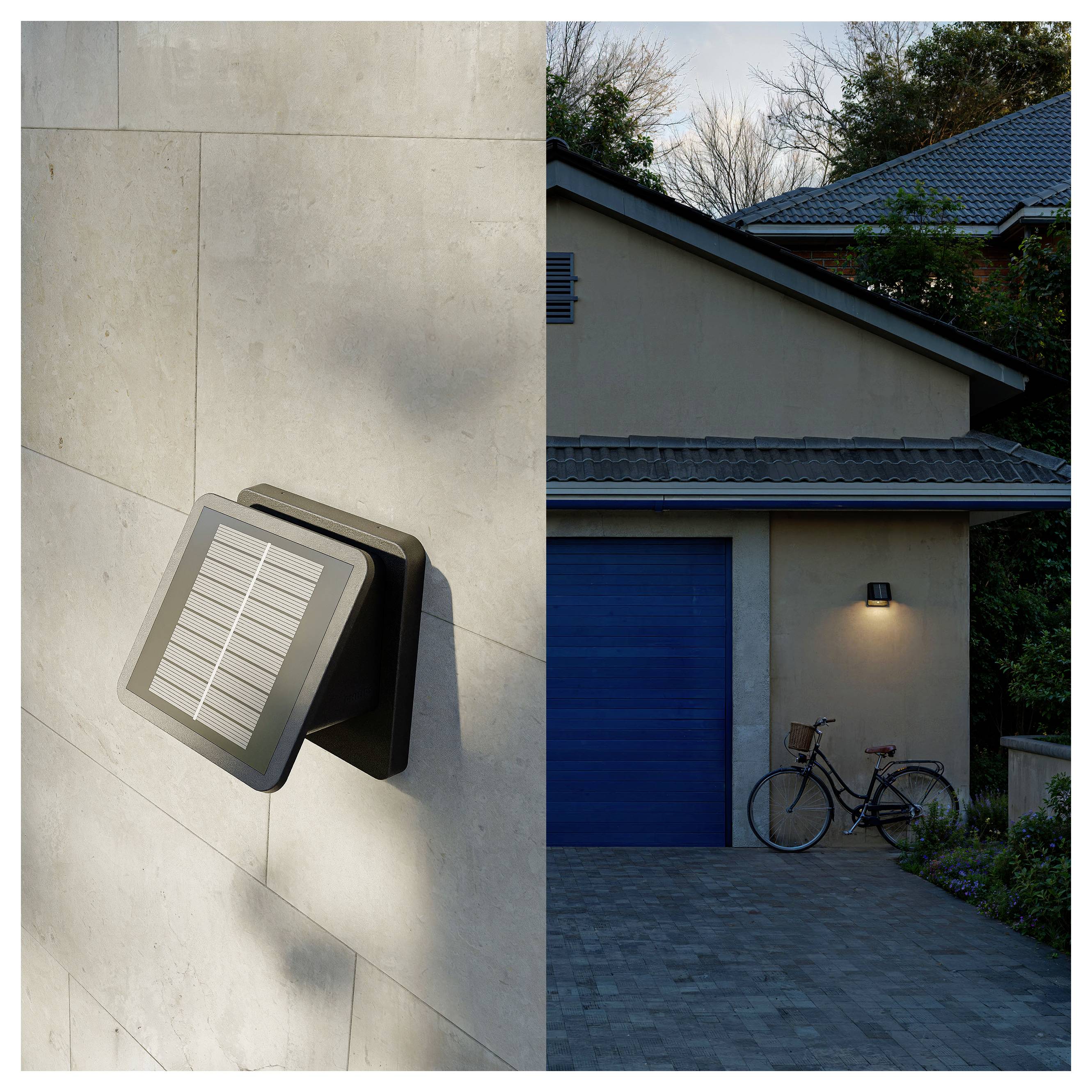 Solarwandleuchte, die an einer Betonaussenwand neben einer Hausgarage montiert ist und bei Einbruch der Dunkelheit die Auffahrt beleuchtet, mit einem Fahrrad in der Nähe.