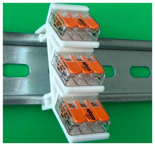 Drei klare elektrische Hebelsteckverbinder auf einer Metallschiene gegen einen grünen Hintergrund montiert.