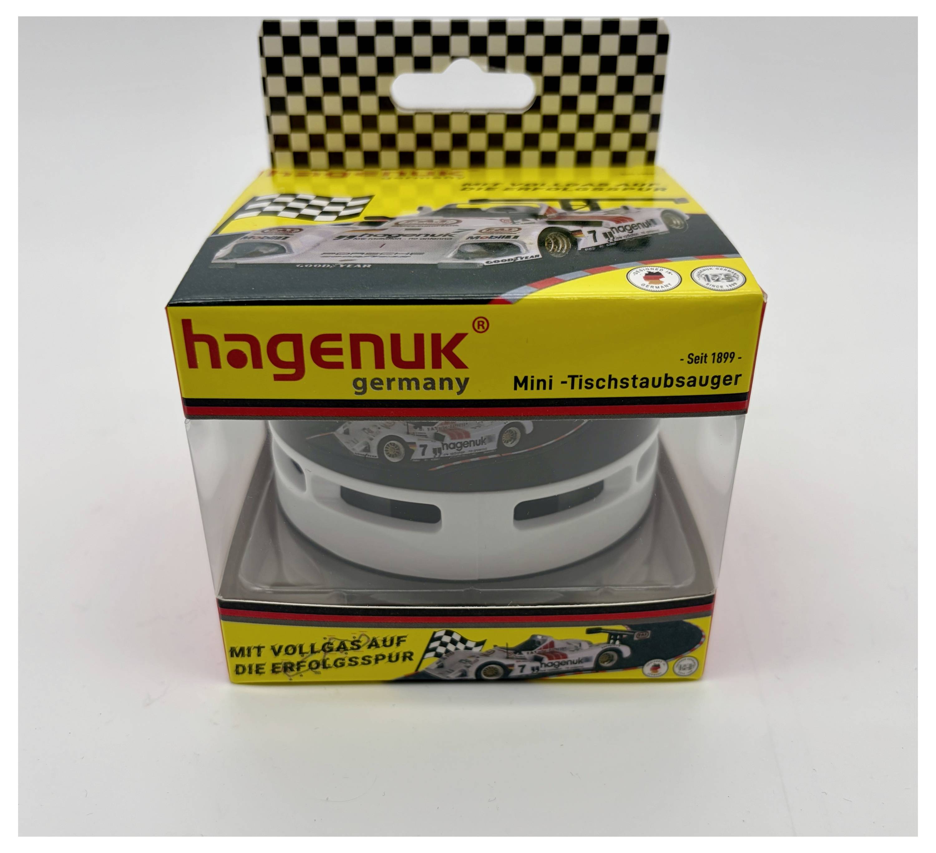 Verpackte HAGENUK Mini-Schreibtischstaubsauger mit Rennwagen-Themenentwurf und klarem Fenster, das das weiße Gerät im Inneren zeigt.