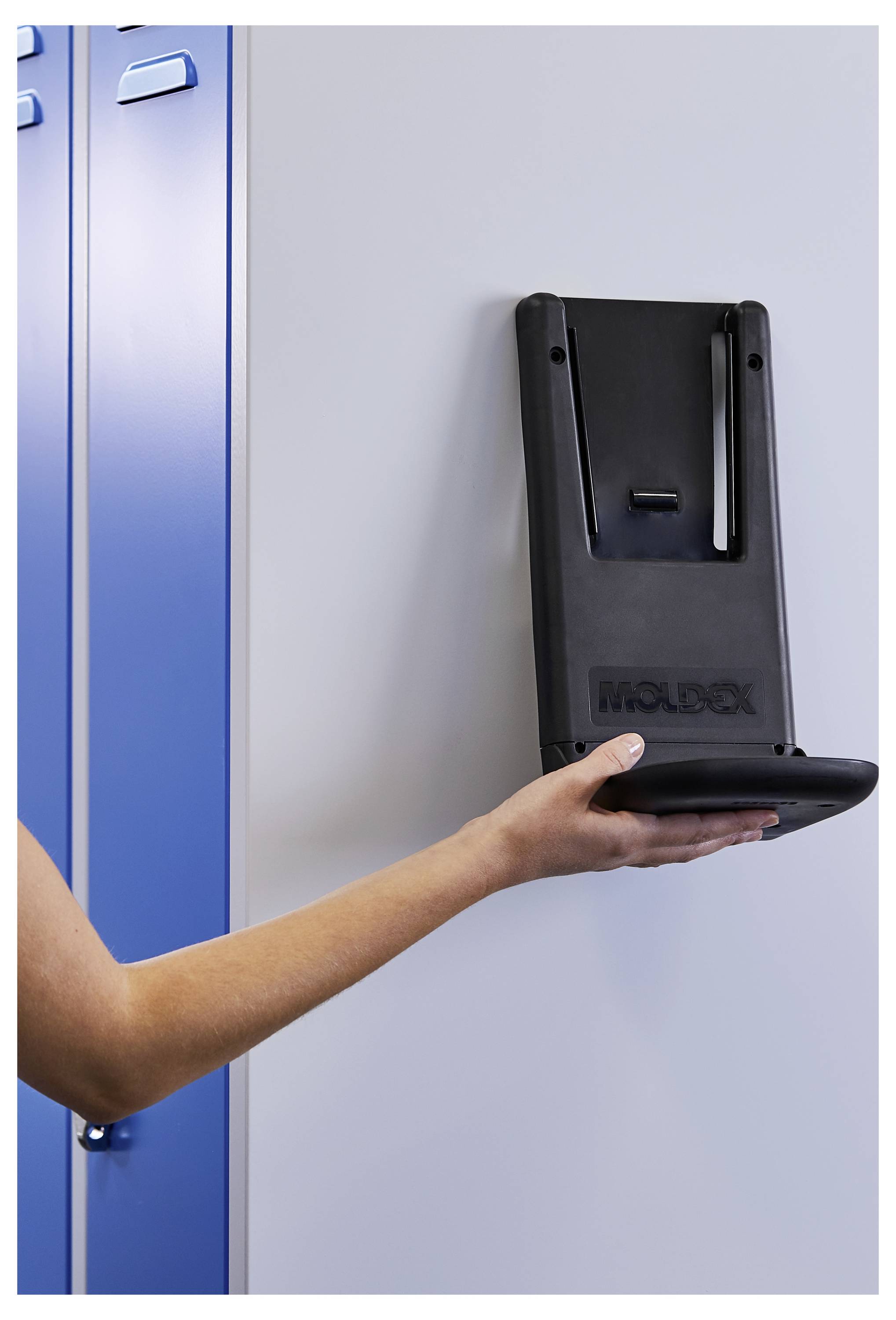 Hand einer Person, die einen schwarzen Helm in einen an der Wand angebrachten Halter neben blauen Spinden einsetzt oder entfernt.
