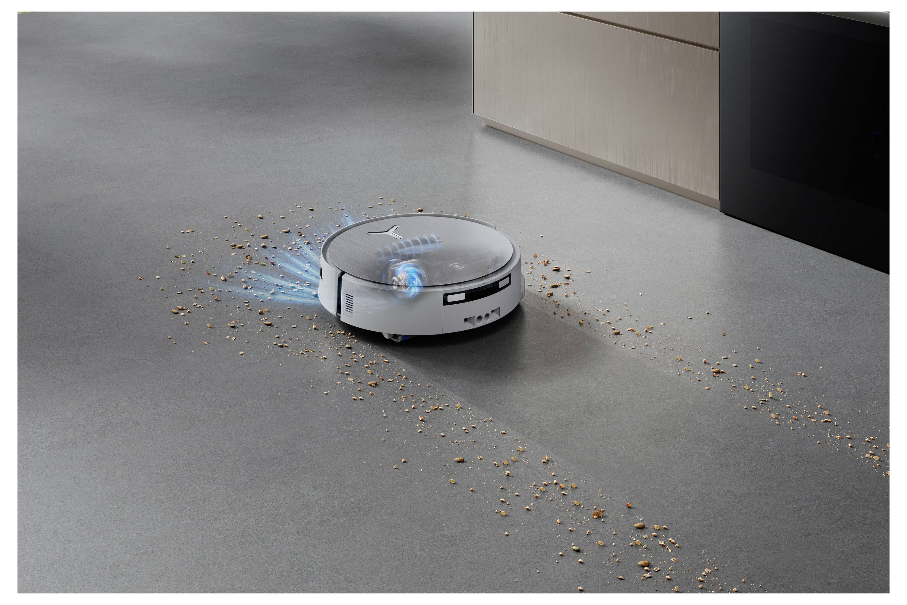 Ein Roboterstaubsauger navigiert über einen Küchenboden und reinigt verstreute Krümel in der Nähe von Schränken.