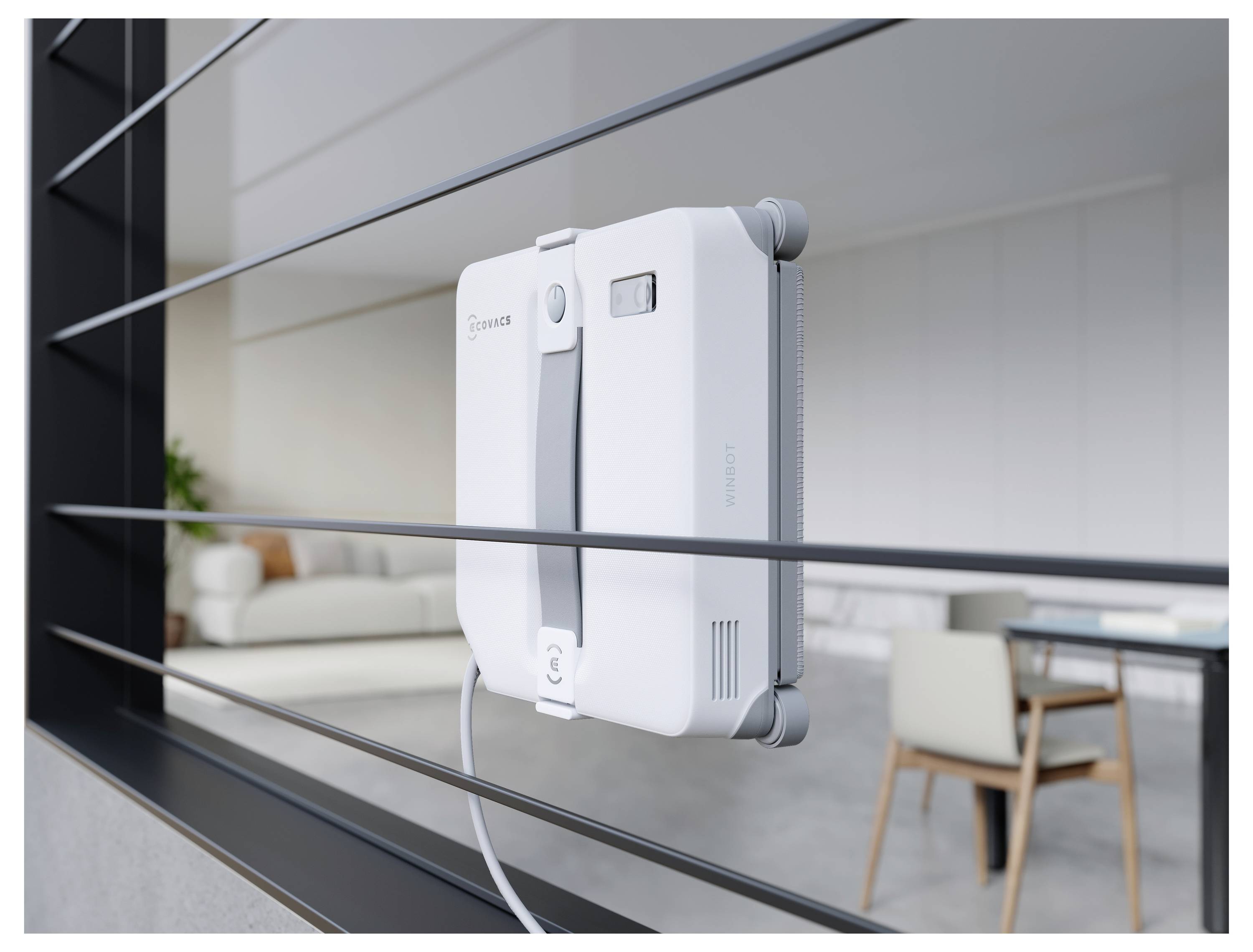 Ein weißes robotisches Fensterreinigungsgerät ist an einem Glasfenster angebracht, mit einem modernen Wohnzimmer dahinter sichtbar.