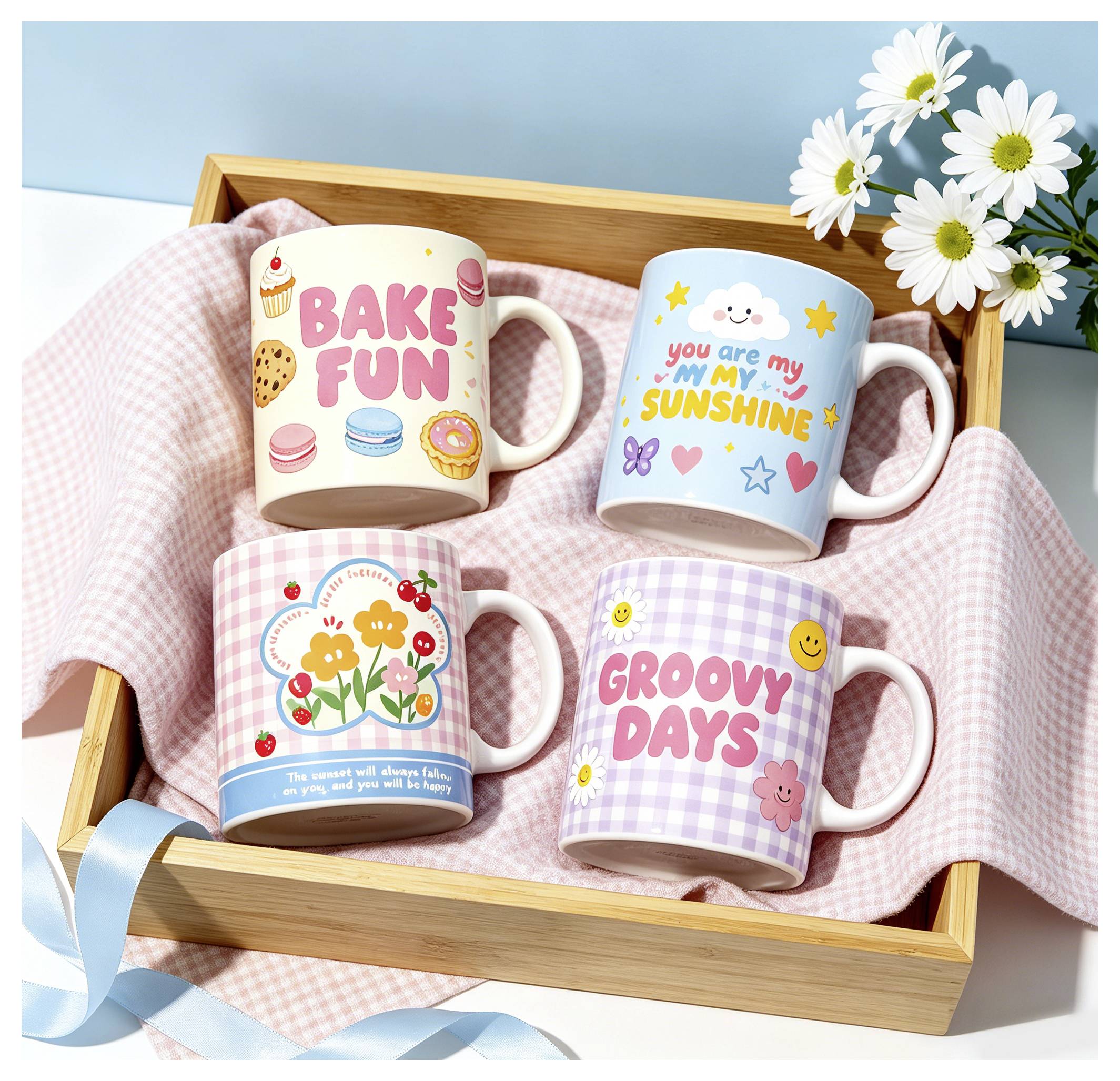Vier dekorierte Tassen in einem Holztablett auf einem rosa Tuch: „BAKE FUN", „you are my sunshine", Blumenmuster und „GROOVY DAYS".