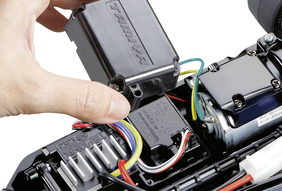 Ein Hand montiert eine schwarze Abdeckung über einem elektronischen Anschluss in einem mechanischen Gerät mit bunten Kabeln.