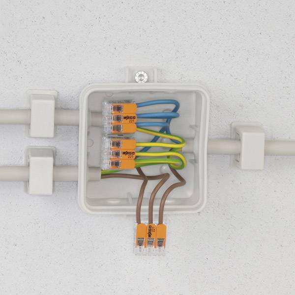 Ein offener Verteilerkasten zeigt verschiedene farbige Kabel, die mit Steckverbindern verbunden sind, an einer grauen Wand montiert.