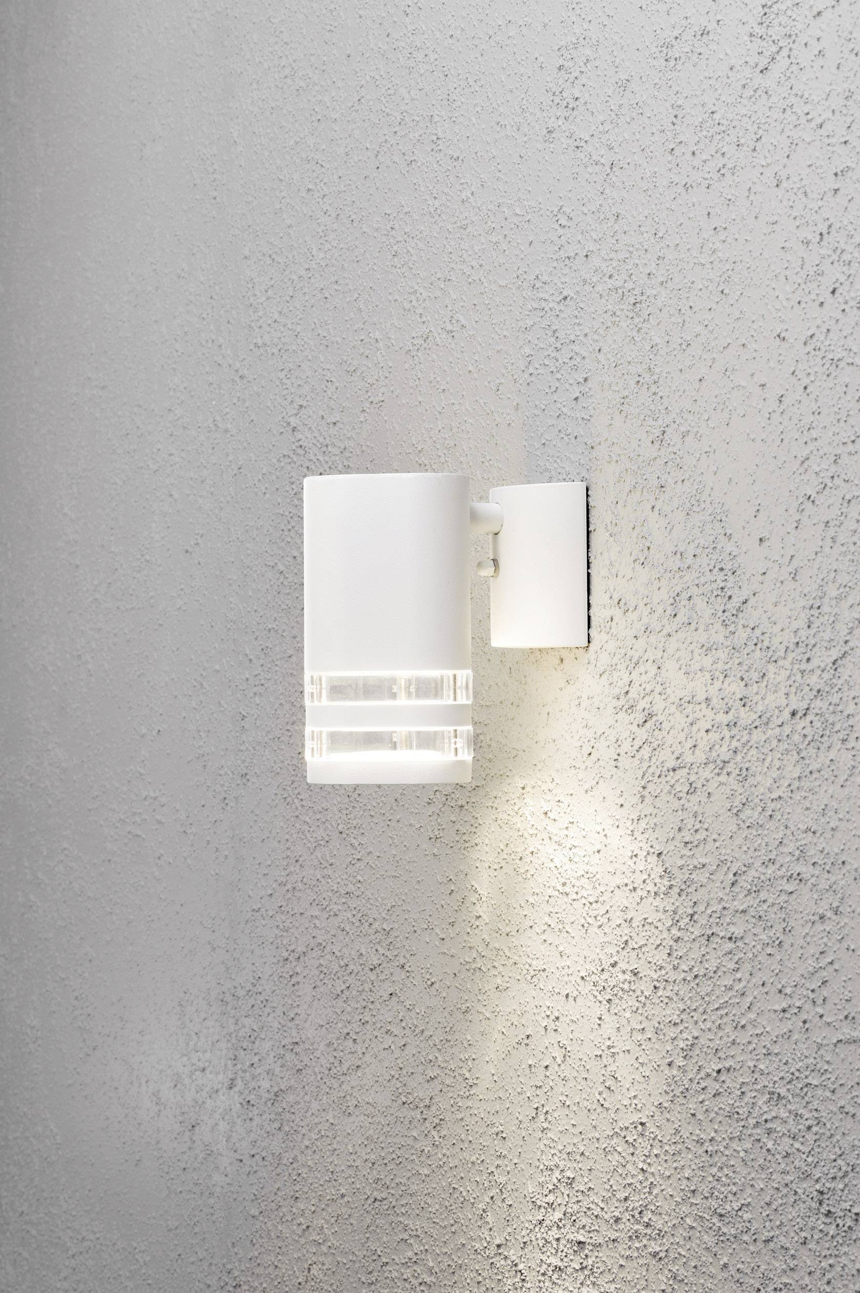 Weiße Wandleuchte vor grauer Wand, die warmes Licht strahlt. Modernes Design mit klaren Linien. Ideal für stimmungsvolle Beleuchtung.