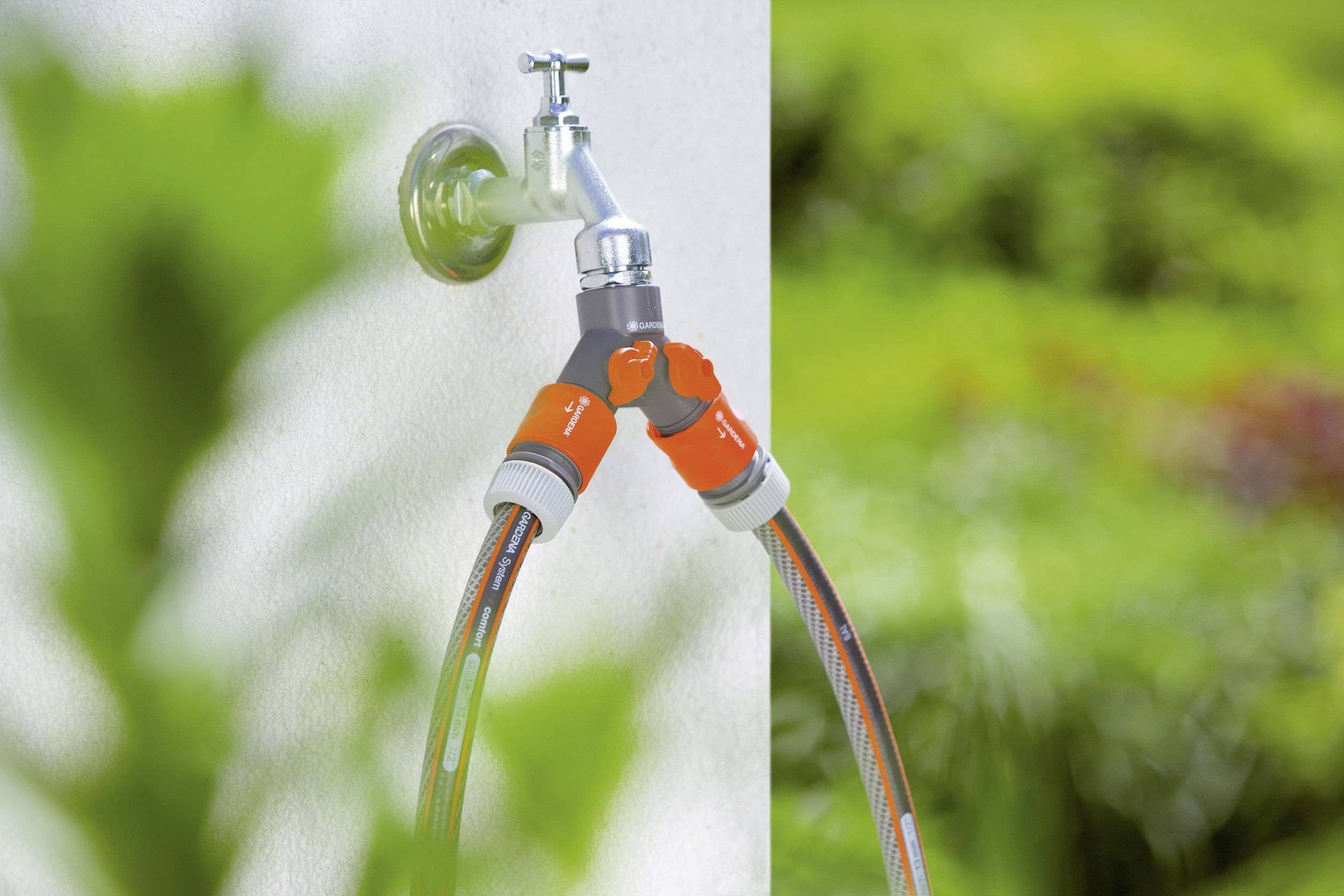 Ein Gartenschlauch-Y-Adapter ist an einen Wasserhahn im Freien angeschlossen, mit zwei Schläuchen, die in unterschiedliche Richtungen führen.