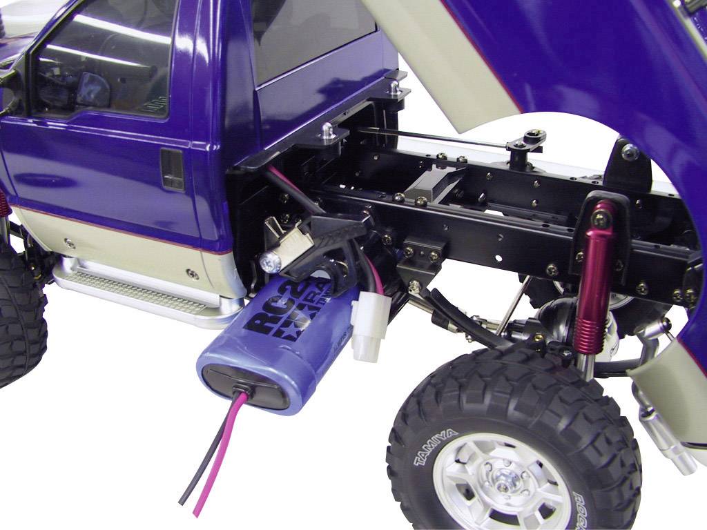 Modellauto mit blauem Gehäuse, offener Motorhaube und sichtbarem Fahrgestell. Elektrische Komponenten und Kabel sind erkennbar.