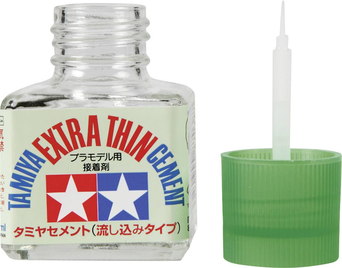 Flasche mit 'Tamiya Extra Thin Cement' Kleber, grüne Kappe daneben.
