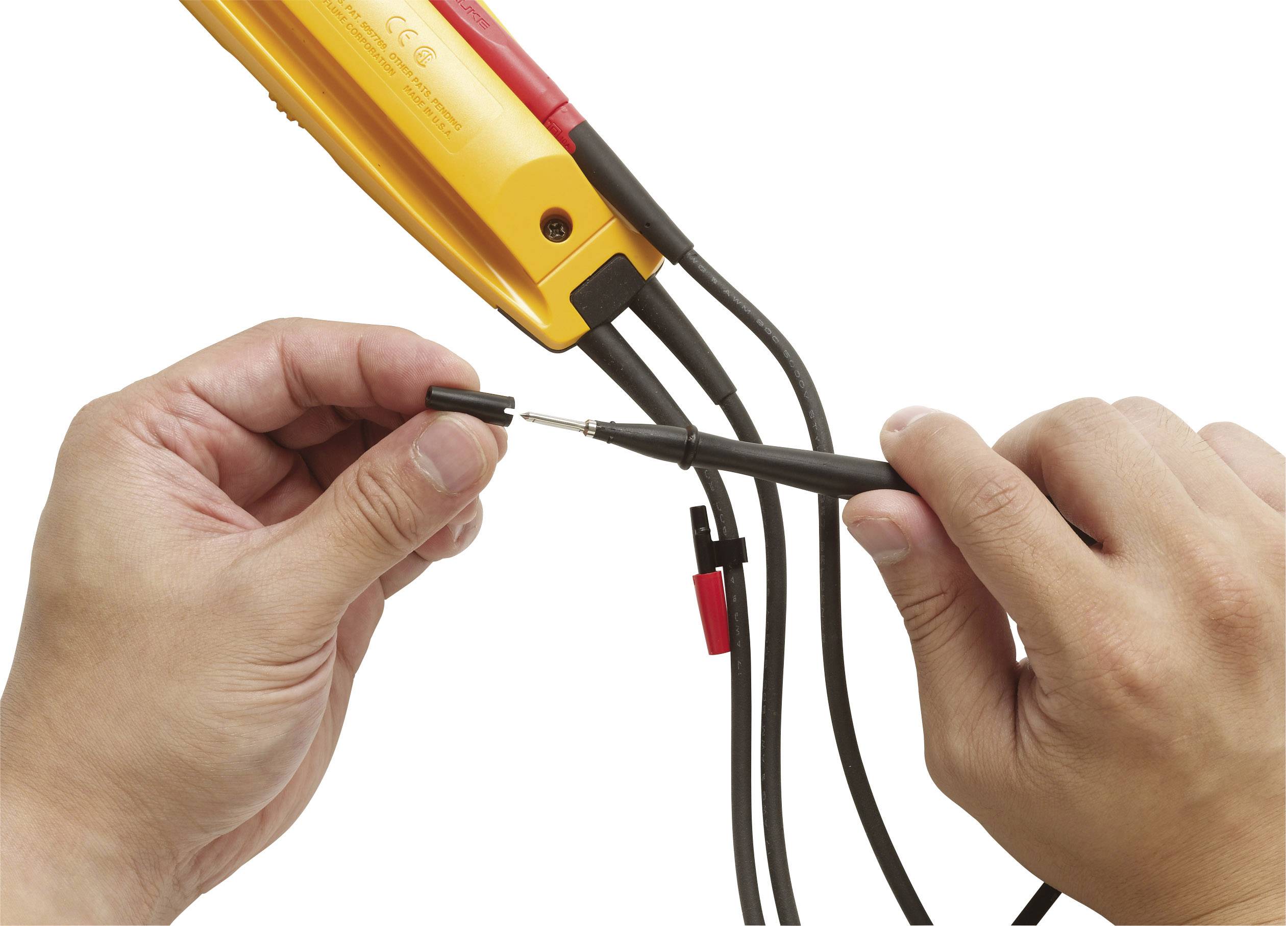 Eine Person hält ein elektrisches Prüfgerät und verbindet Kabel mit einer Messspitze, um die Spannung zu messen.