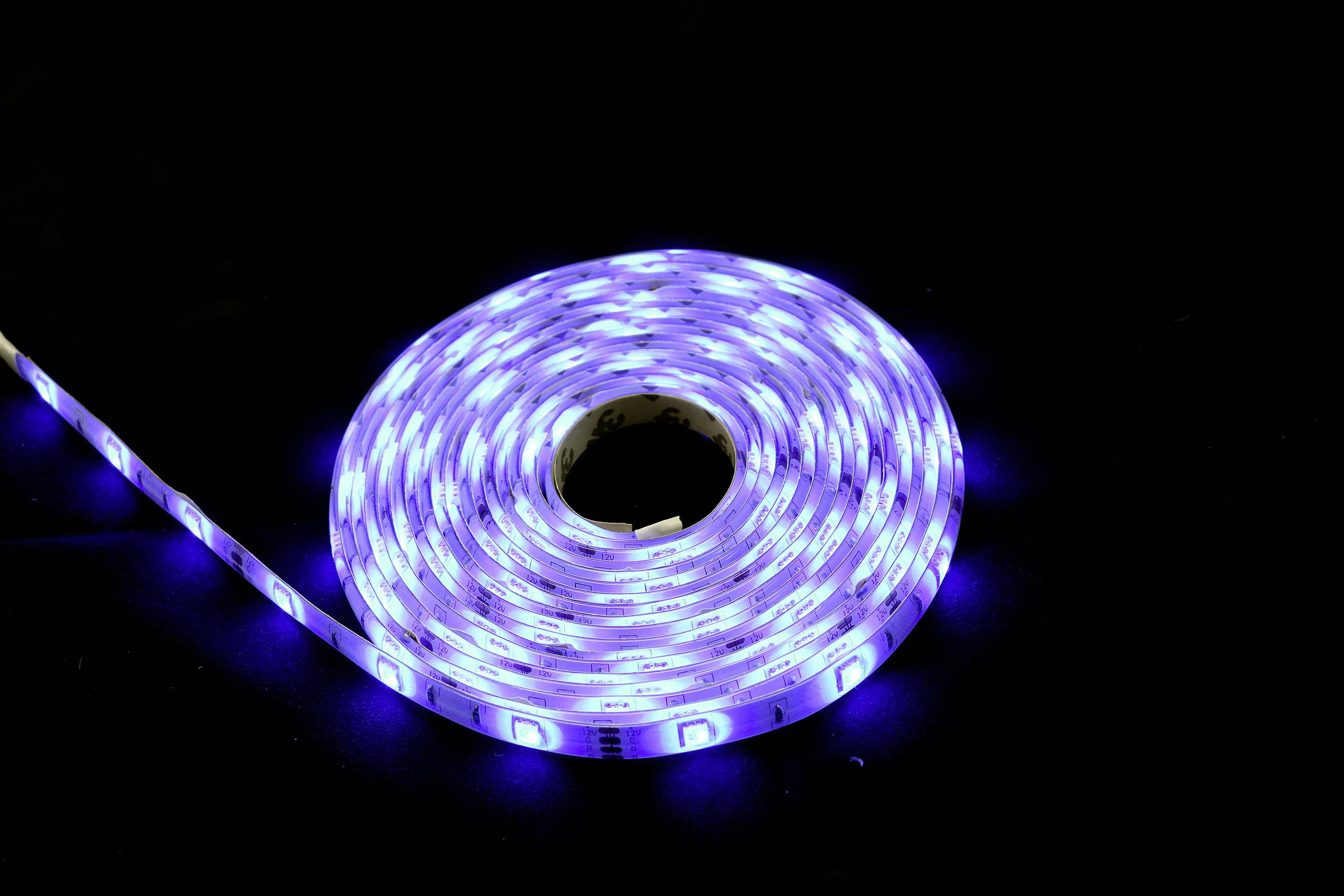 Eine aufgerollte, leuchtende LED-Lichterkette mit blauem Licht auf schwarzem Hintergrund.