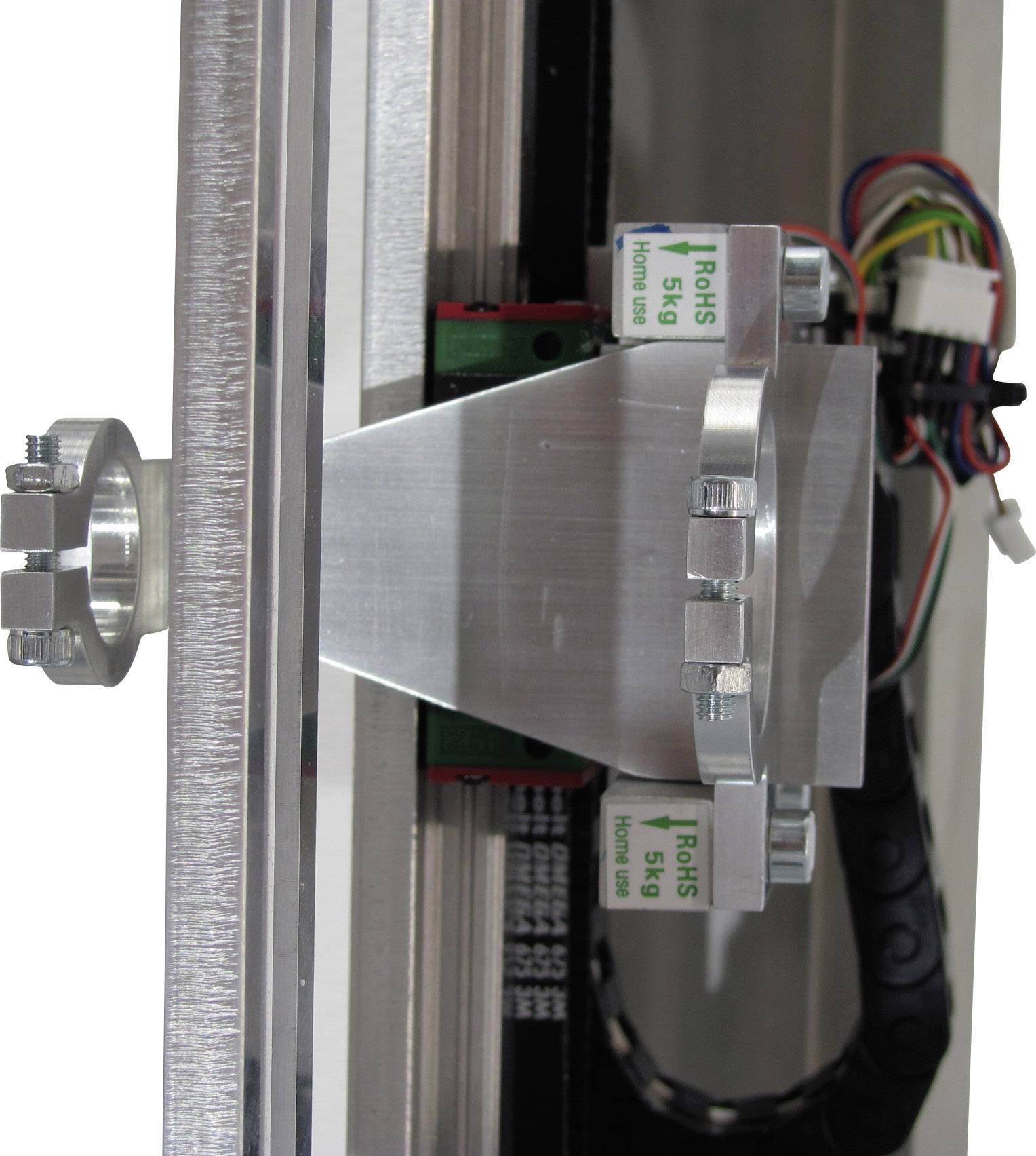 Ein Seitenansicht-Foto zeigt eine metallische Vorrichtung mit Kabeln und zwei grünen Aufklebern, die 'RoHS 5kg' anzeigen.