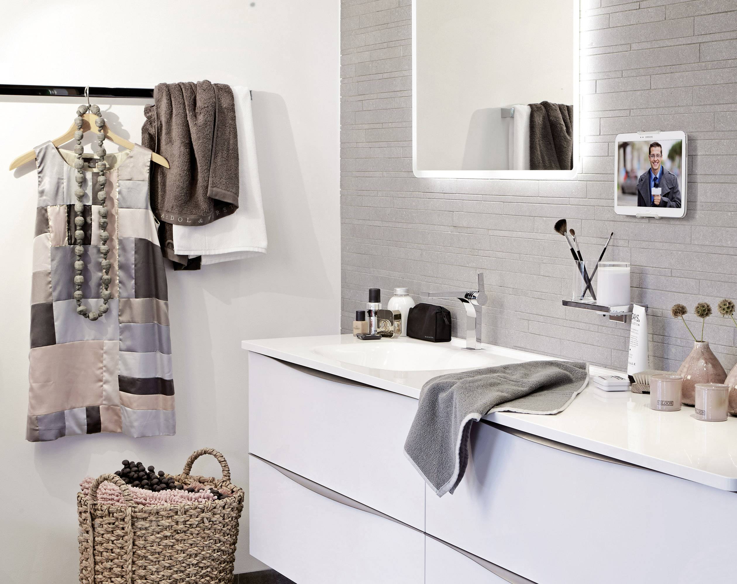 Ein stilvoll eingerichtetes Badezimmer mit moderner, weißer Waschtischplatte, hängendem Kleid und dekorativem Korb.