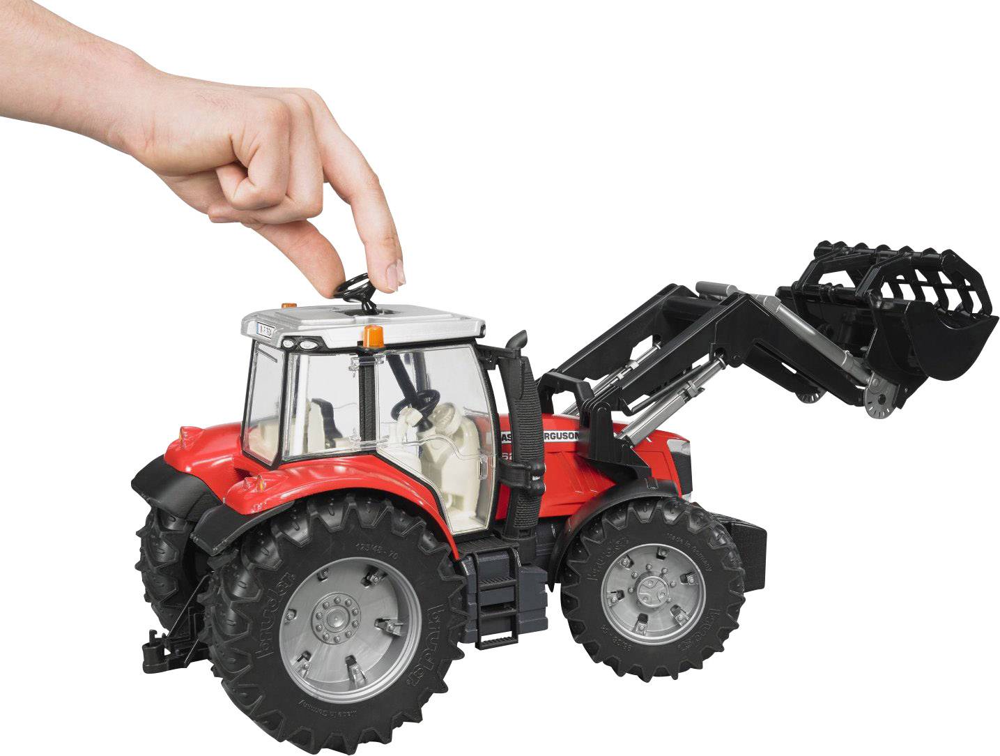 Ein rotes Spielzeugtraktor-Modell mit beweglicher Schaufel wird von einer Hand oben gehalten. Der Fokus liegt auf der Handhabung des Modells.
