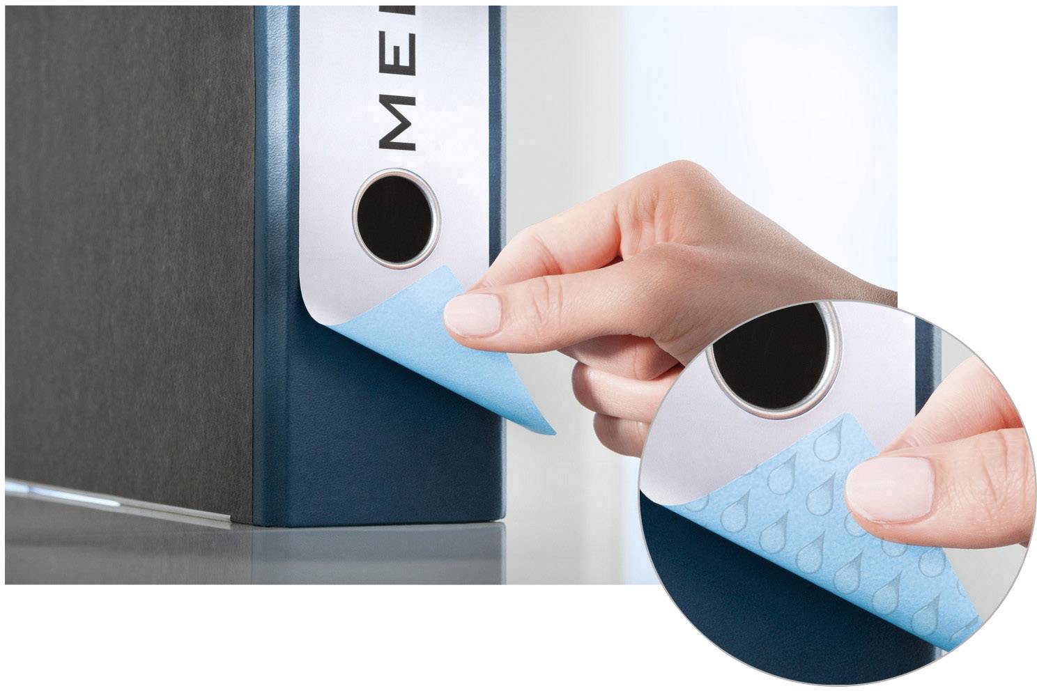 Ein blauer Ordner wird mit einem kleinen blauen Haftnotiz beschriftet. Eine Hand klebt den Notiz auf, Nahaufnahme von Fingern und Haftnotiz.