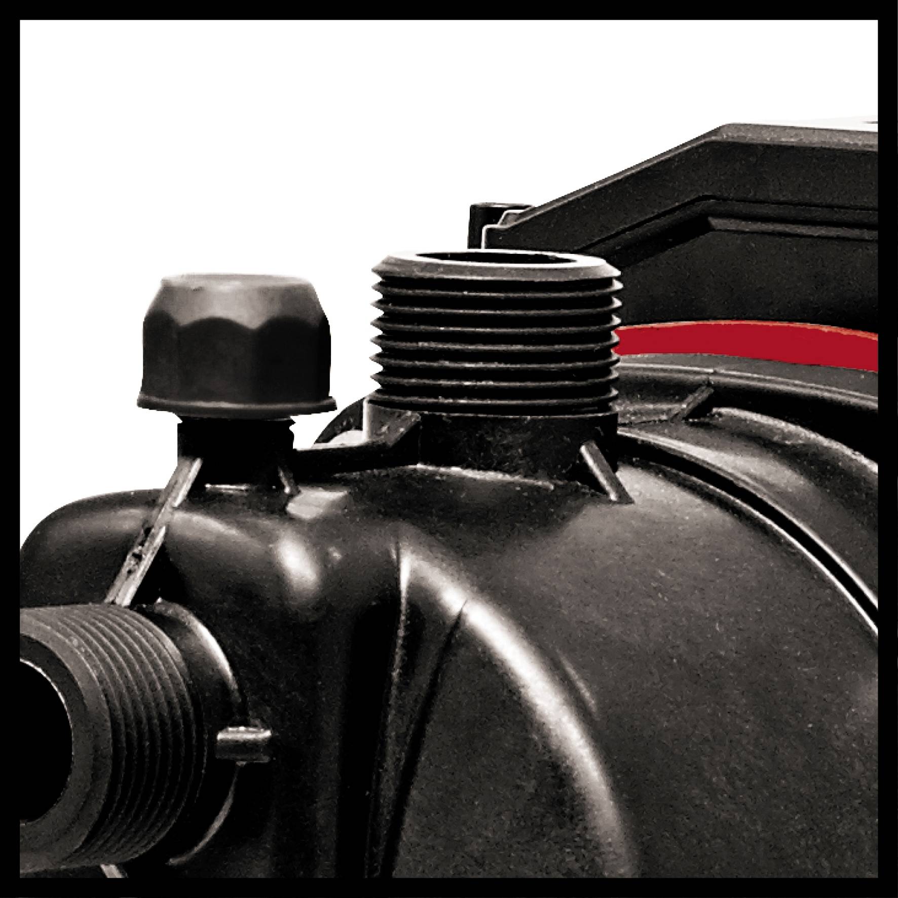 Nahaufnahme eines industriellen Maschinenteils mit schwarzen Metallanschlüssen und rotem Element auf der rechten Seite.