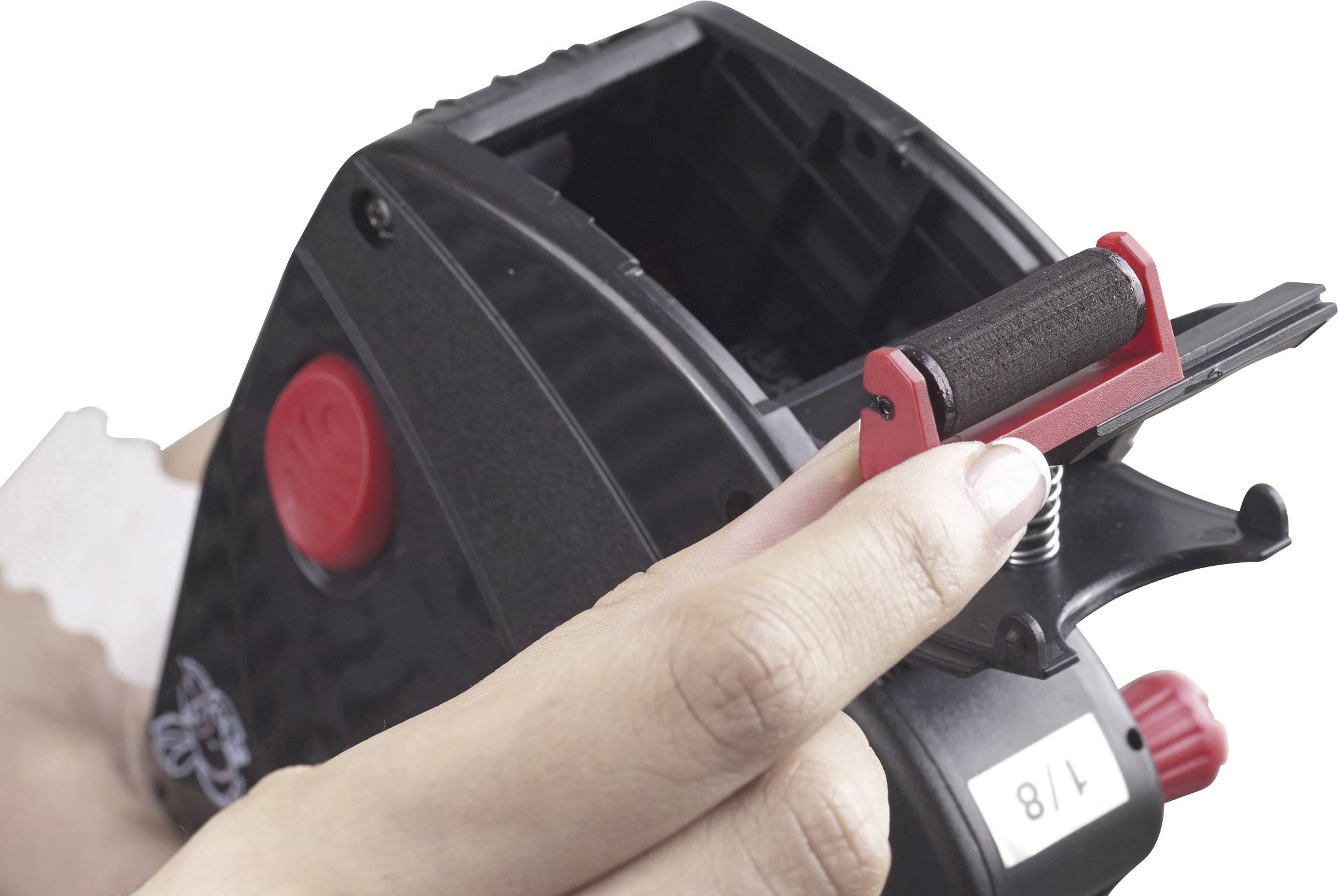 Eine Person hält einen schwarzen Etikettierer, der zum Bedrucken von Preisetiketten verwendet wird. Ein weißes Etikett wird gerade eingelegt.