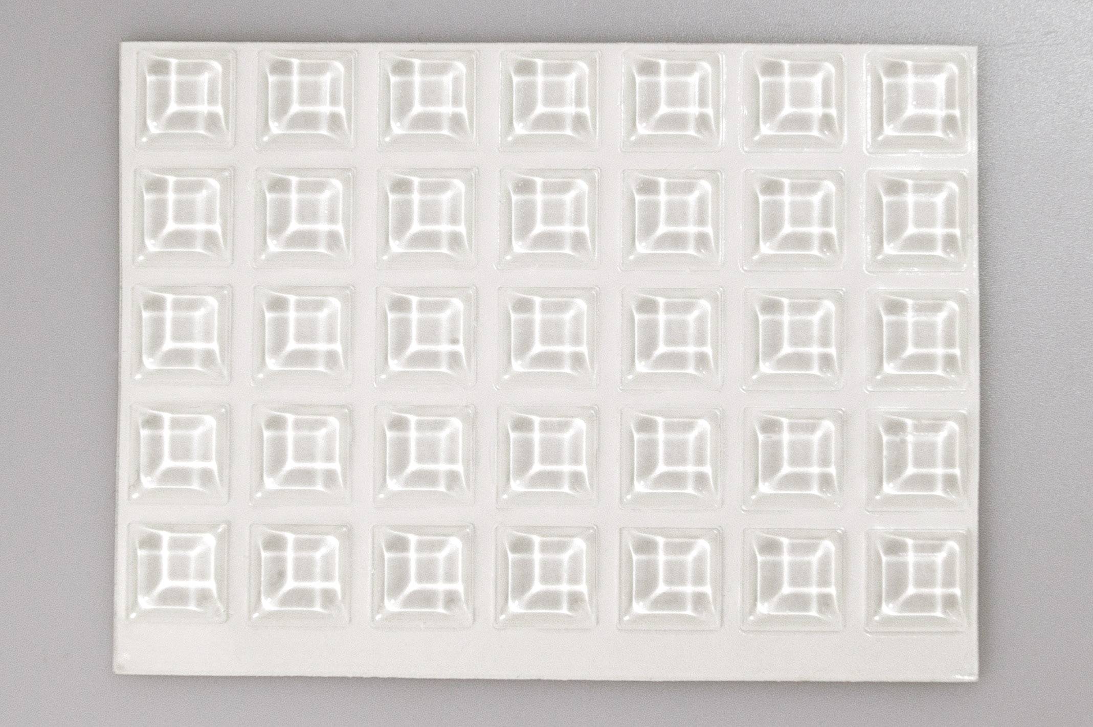 Weiße quadratische Tafelschokolade mit 35 einzelnen Stücken auf grauem Hintergrund.