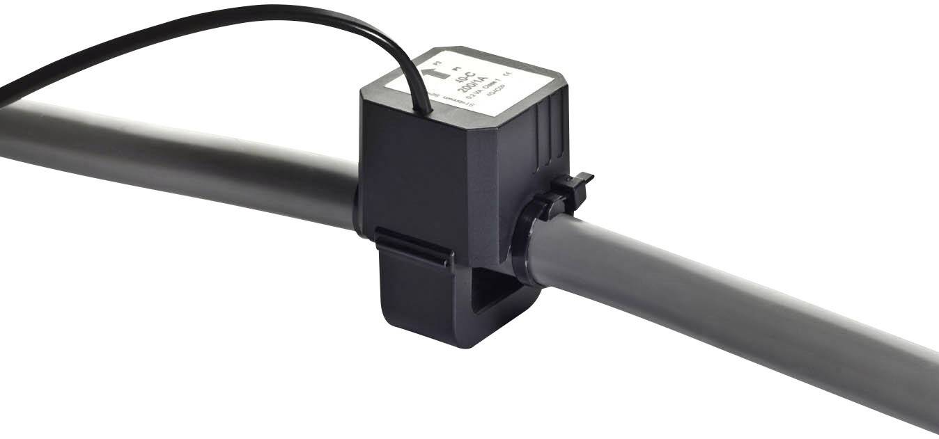 Ein schwarzer Sensor ist an einem grauen Rohr befestigt. Ein Kabel geht vom Sensor ab. Der Sensor misst Durchfluss oder andere Daten.