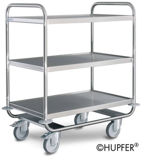 Edelstahl-Servierwagen mit drei Ablageflächen und vier Schwenkrollen auf glänzendem Boden. Markenname rechts unten im Bild.