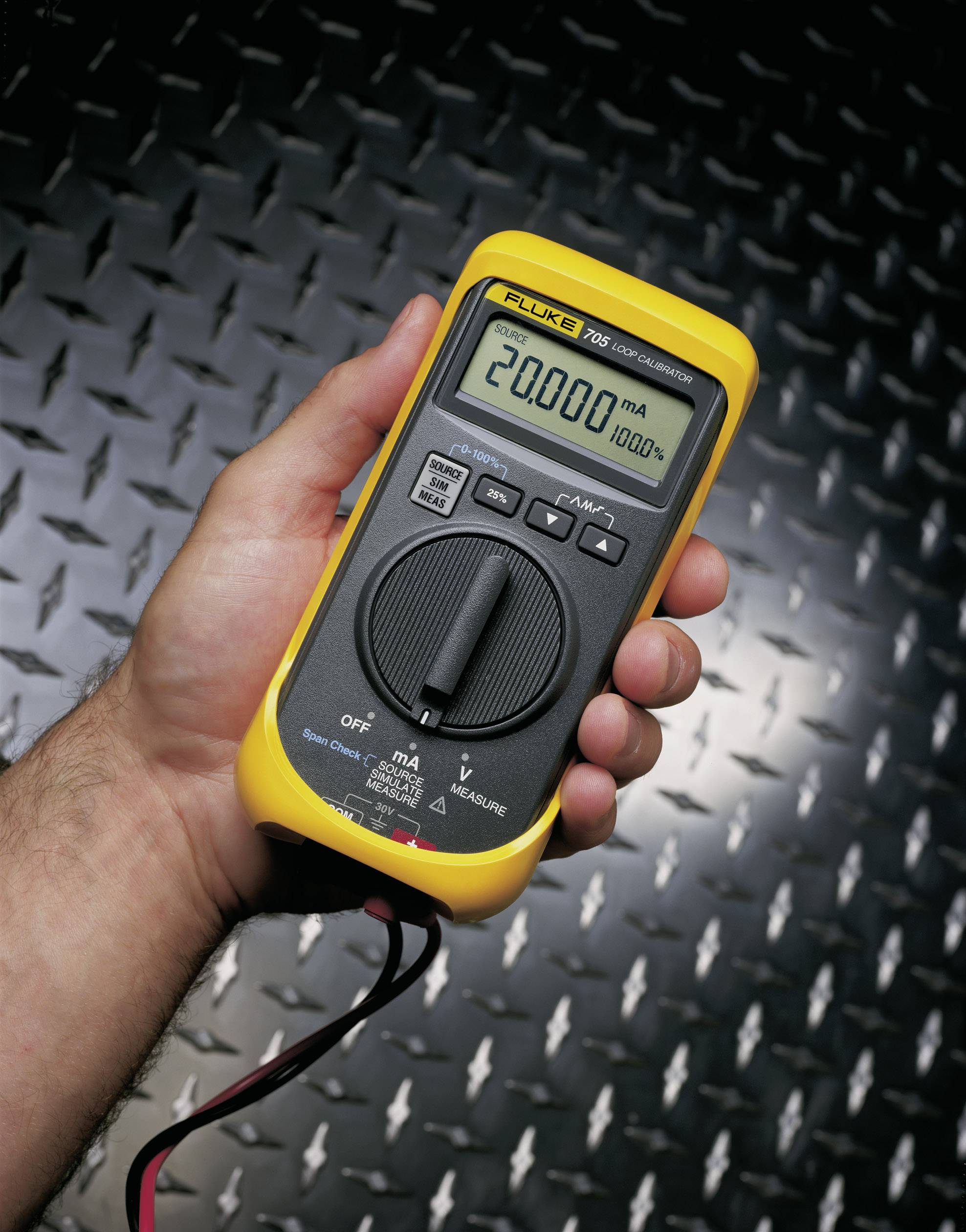 Eine Hand hält ein digitales Multimeter, das 20.000 mA auf einem metallischen Hintergrund anzeigt.