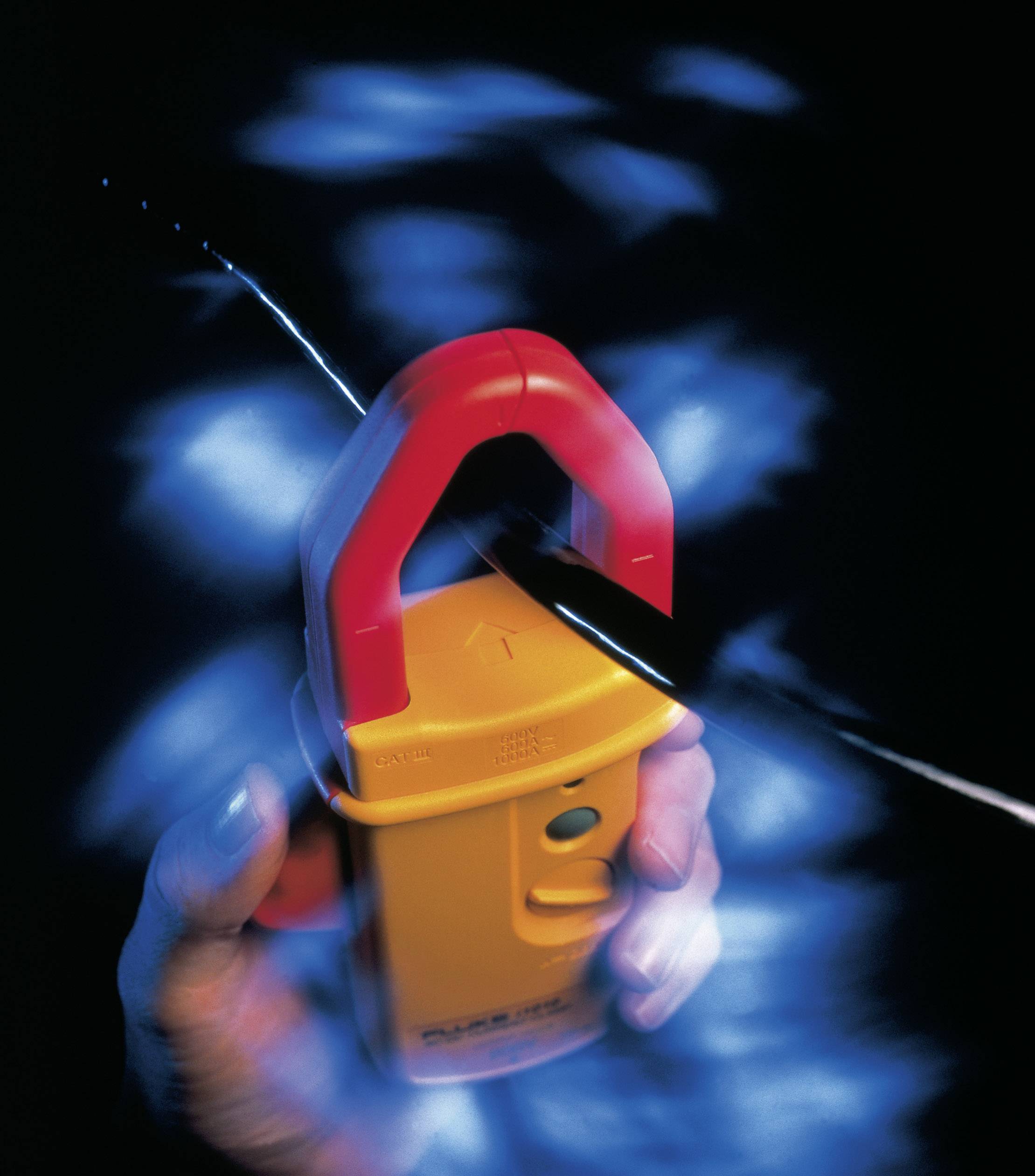 Hand hält ein gelbes elektrisches Prüfgerät mit rotem Griff, während es einen schwarzen Draht umschließt; blaues Licht leuchtet auf.