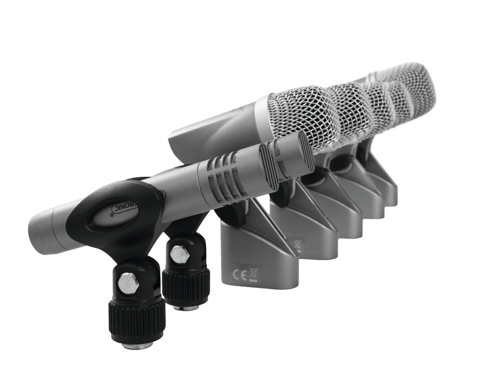 Vier graue Mikrofone stehen nebeneinander in einer diagonalen Reihe, ausgerichtet für professionelle Audioaufnahmen.