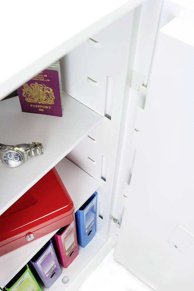 Geöffneter Schrank mit einem britischen Reisepass, einer Armbanduhr und Aktenordnern in verschiedenen Farben.