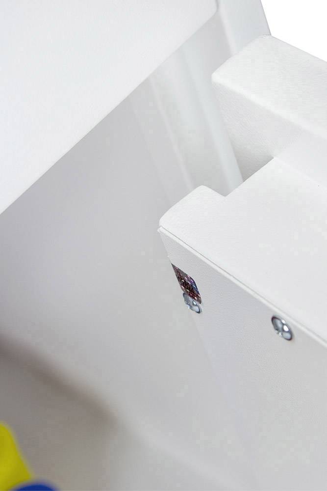 Eine weiße, glänzende Oberfläche mit silbernen Schrauben. Im Hintergrund sind unscharfe farbige Gegenstände sichtbar.