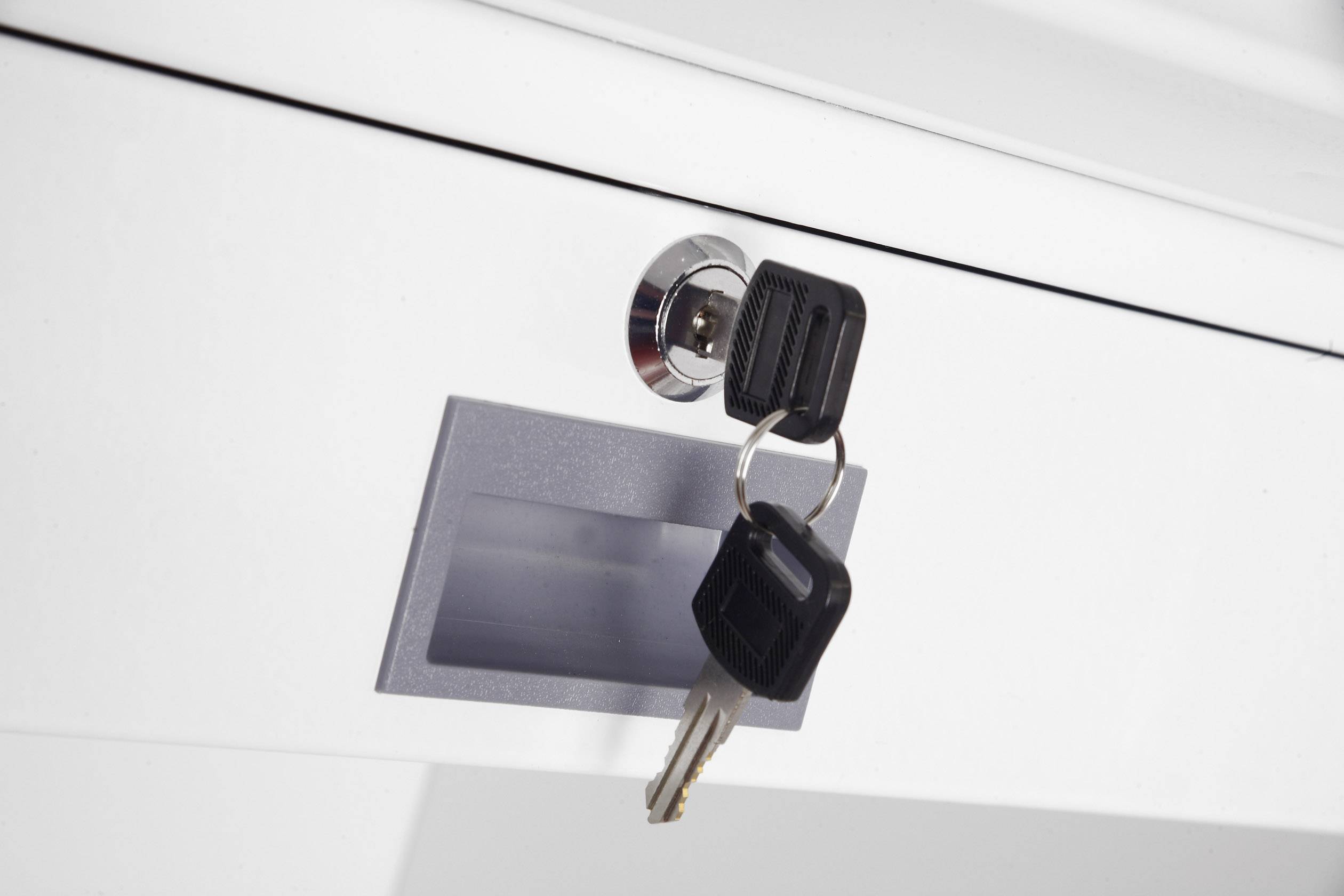 Schlüssel steckt im Schloss einer weißen Schublade.