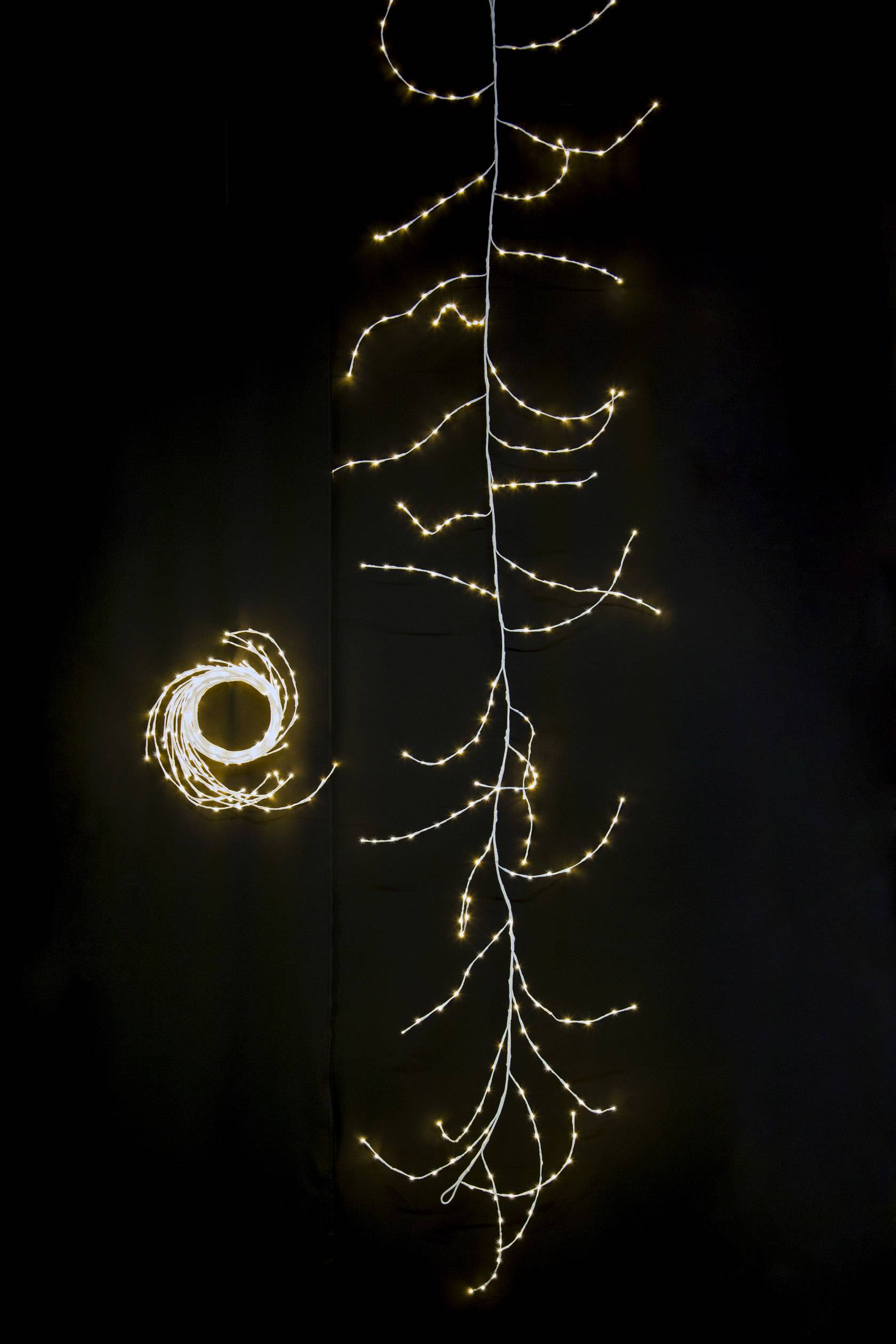 Lichterkette in Form eines Astes und eines Kreises auf schwarzem Hintergrund, strahlt warmes, gedämpftes Licht aus.