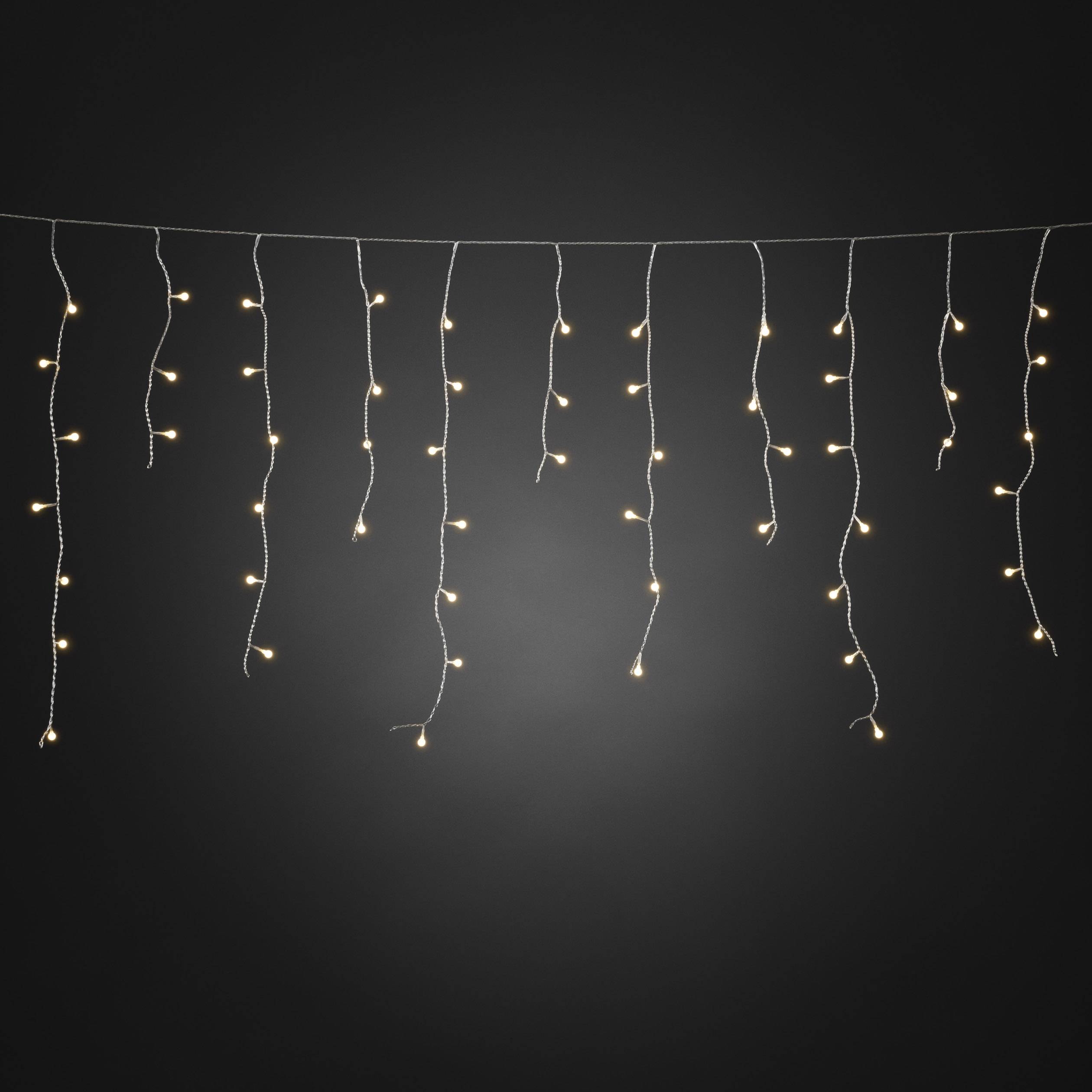 Lichterkette mit kleinen, warmweiß leuchtenden Lichtern hängt horizontal vor einem dunklen Hintergrund.