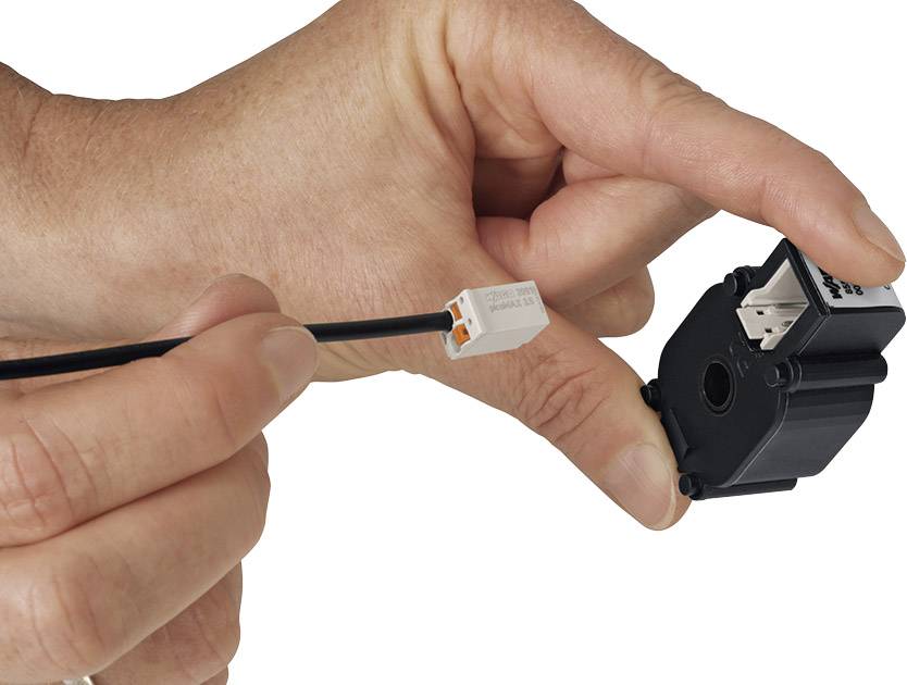 Eine Hand hält einen elektrischen Sensor in der Nähe eines Kabels mit einem Stecker. Der Sensor steht kurz vor dem Anschluss.