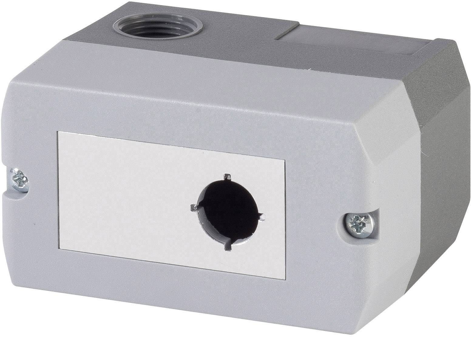 Ein rechteckiges, graues Kunststoffgehäuse mit einer runden Öffnung in der Mitte und zwei Schrauben an den Seiten.