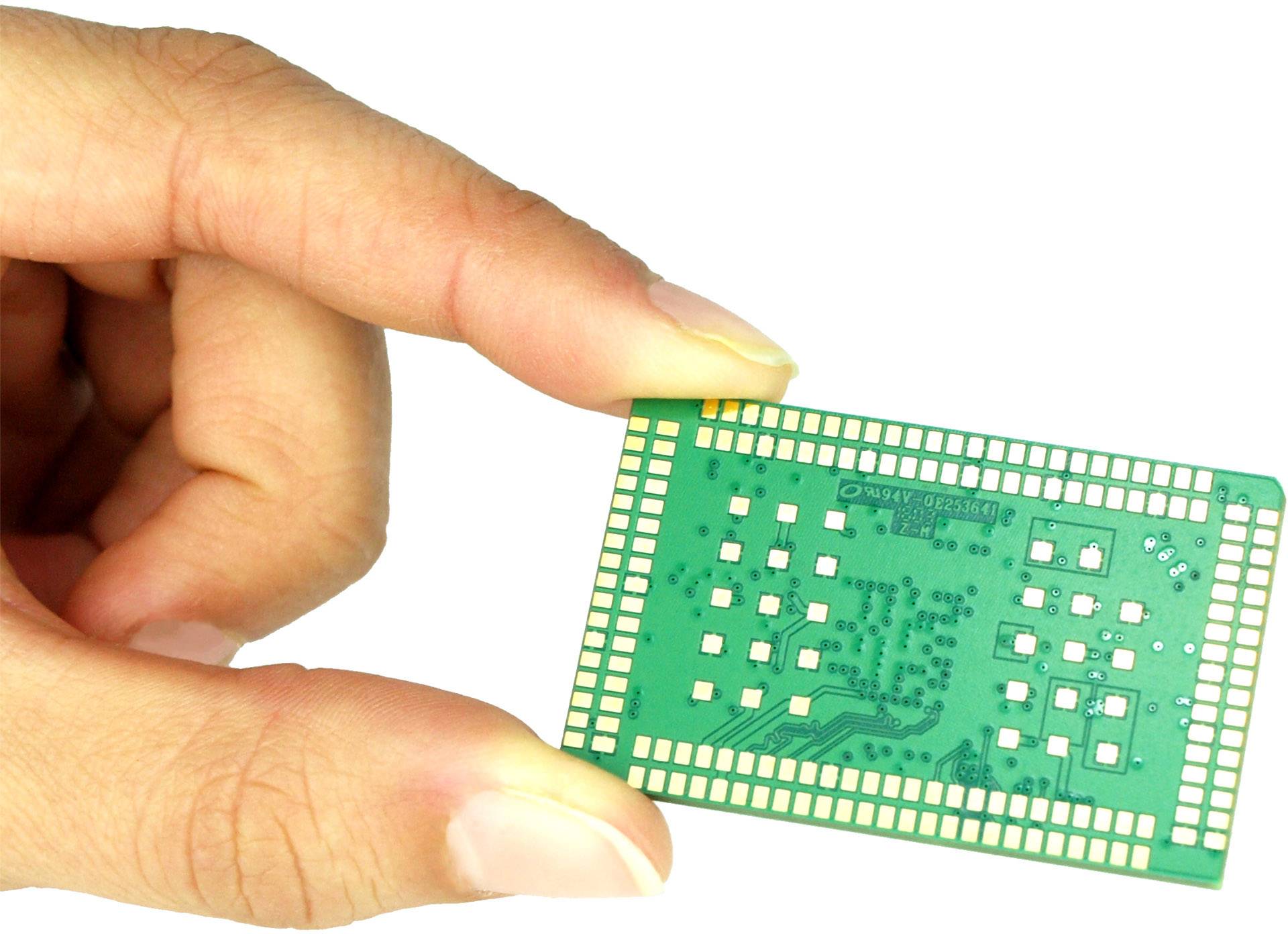 Eine Hand hält einen grünen Mikrochip mit sichtbaren Schaltungen und Anschlüssen. Der Chip ist klein und rechteckig.