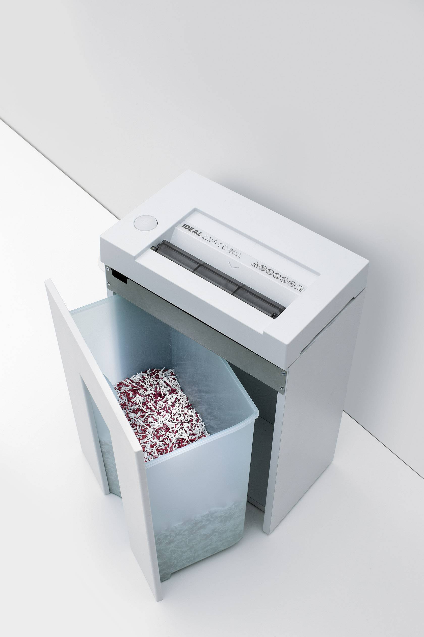 Ein Aktenvernichter zerreißt Papierstreifen in einem Behälter. Das Gerät befindet sich in einer modernen Büroumgebung.