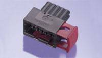 Ein schwarzer elektrischer Stecker mit mehreren Pins und einem roten Verriegelungselement, platziert auf einem hellen Hintergrund.