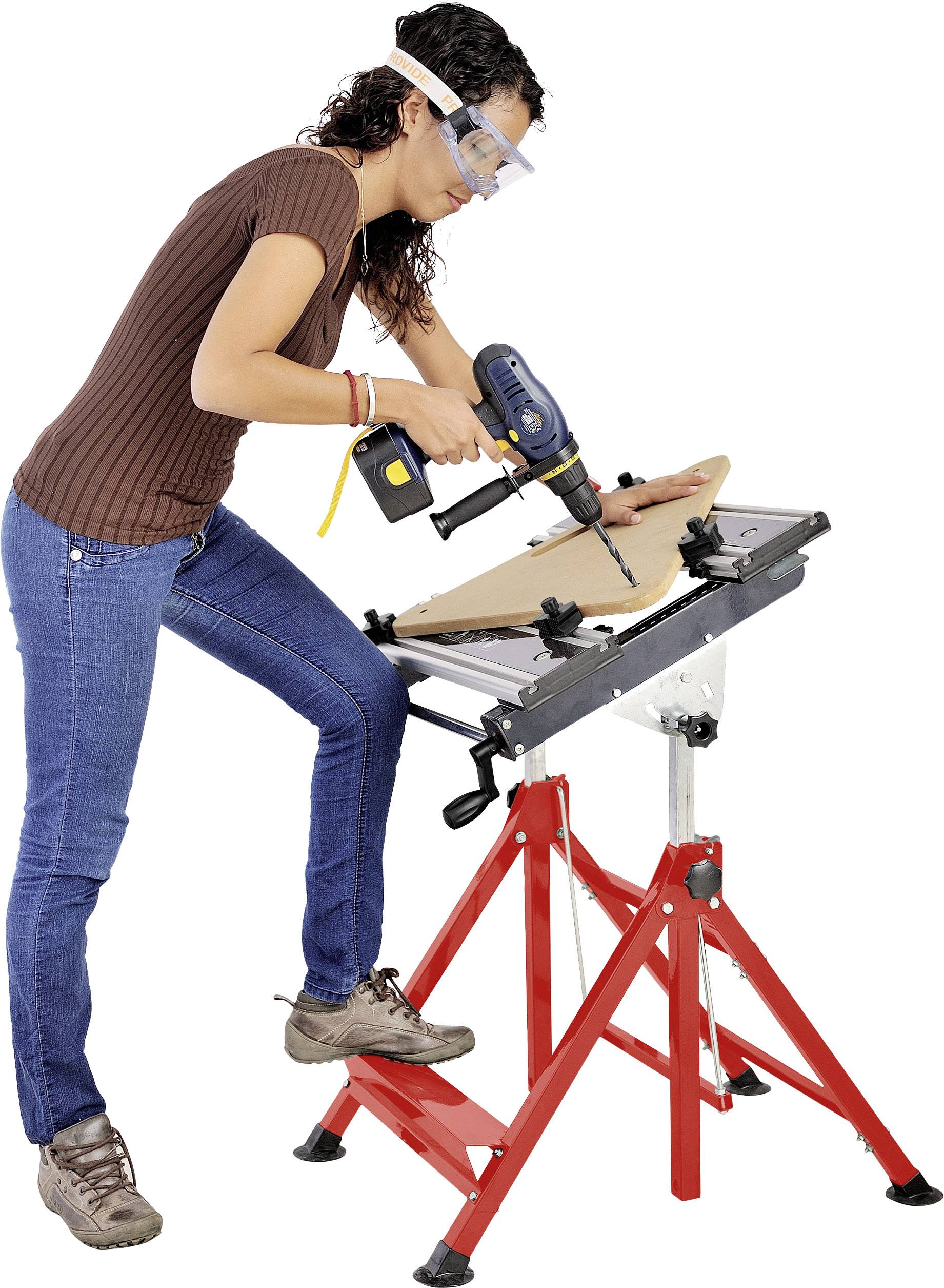 Eine Person trägt Schutzbrille und verwendet eine elektrische Bohrmaschine, um ein Brett auf einem roten Arbeitstisch zu bearbeiten.
