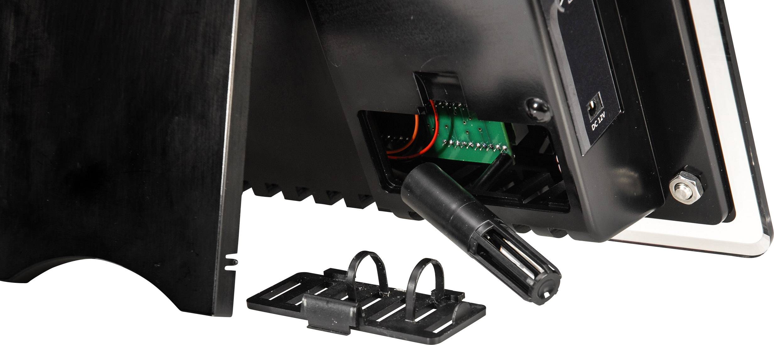 Hinteransicht eines elektronischen Geräts mit offenem Gehäuse. Sichtbare Kabel und Anschlüsse. Zubehörteile liegen daneben.