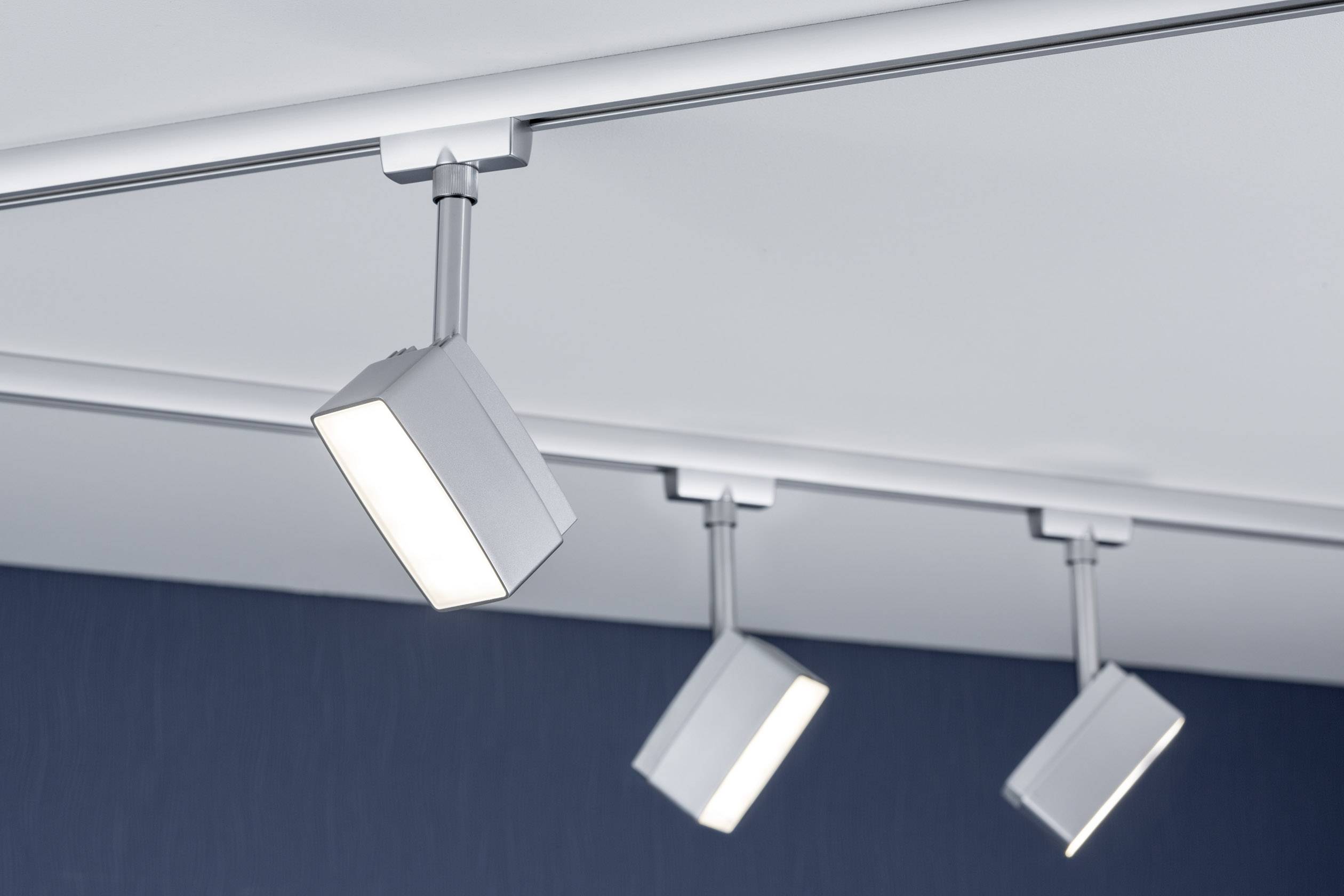 Drei moderne Deckenleuchten in einem Raum, die gleichmäßig gerichtetes Licht auf den Boden werfen.