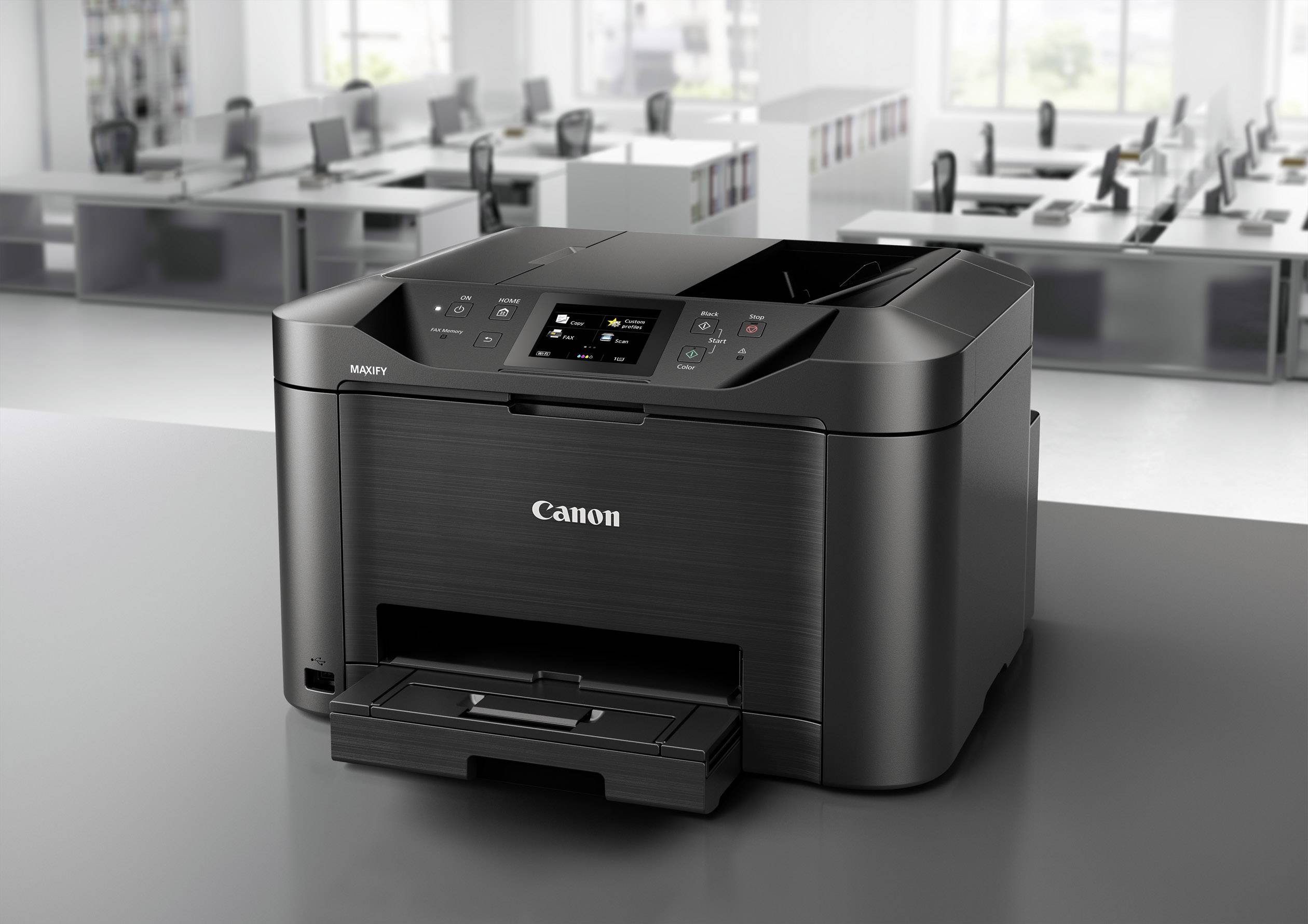 Ein schwarzer Drucker steht auf einem Tisch in einem modernen Büro mit mehreren Schreibtischen und Stühlen im Hintergrund.