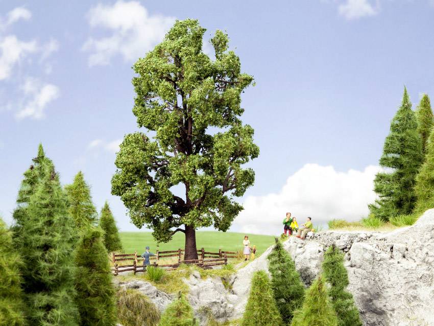Eine Miniaturlandschaft mit einem großen Baum in der Mitte, umgeben von Wiesen und Nadelbäumen. Einige Figuren wandern auf einem felsigen Pfad.