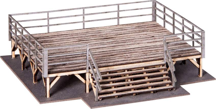 Holzplattform mit Geländer und Treppe auf einer Seite. Die Oberfläche wirkt verwittert, als ob sie im Freien genutzt wird.