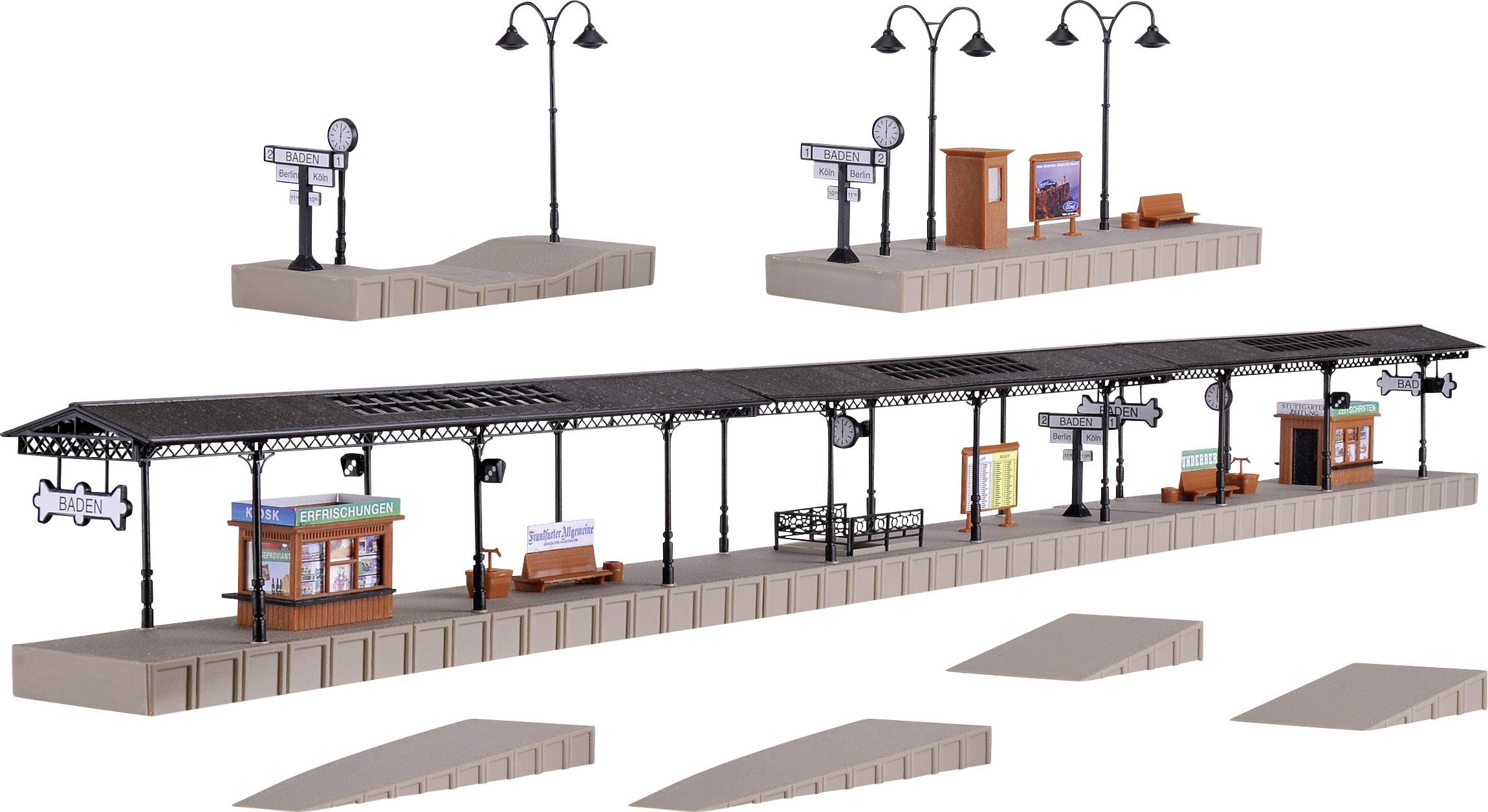 Spielzeugeisenbahnplattform mit Bahnsteigen, Laternen, Sitzbänken und Bahnhofsschildern, zeigt eine Miniaturszene eines Bahnhofs.