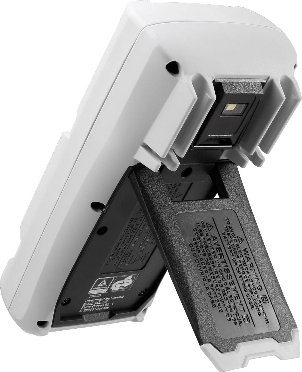 Ein batteriebetriebenes Gerät, leicht schräg von der Seite fotografiert, zeigt das geöffnete Batteriefach und darunterliegende Warnhinweise.