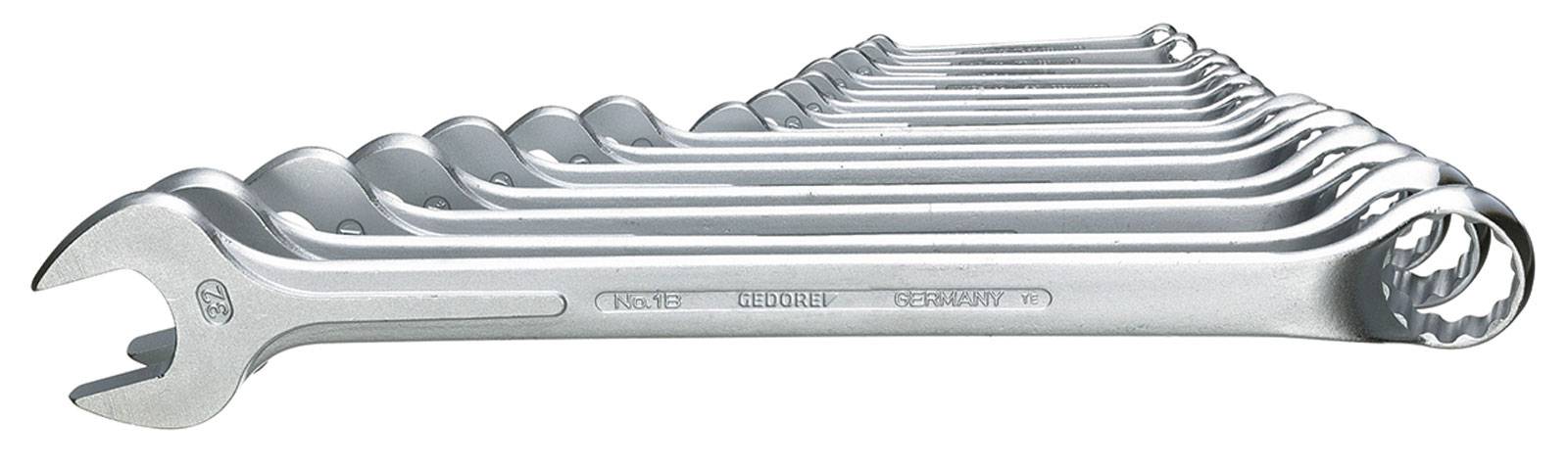 Ein Satz Schraubenschlüssel in verschiedenen Größen, geordnet von klein nach groß, aus Metall, auf einer weißen Oberfläche liegend.
