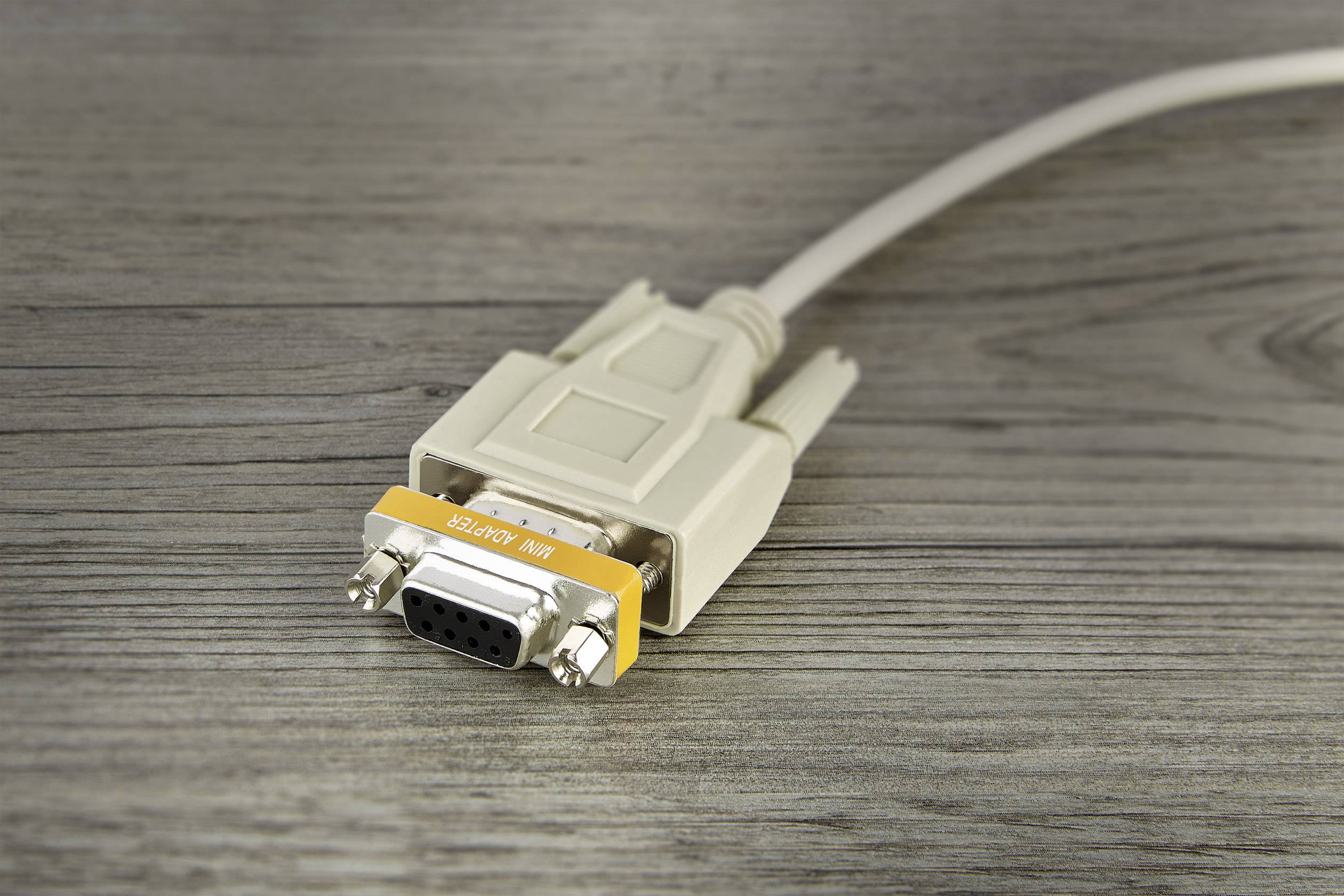 Ein weißes VGA-Kabel mit einem orangefarbenen Band, auf dem 'Nullmodem' steht, liegt auf einer Holzoberfläche.