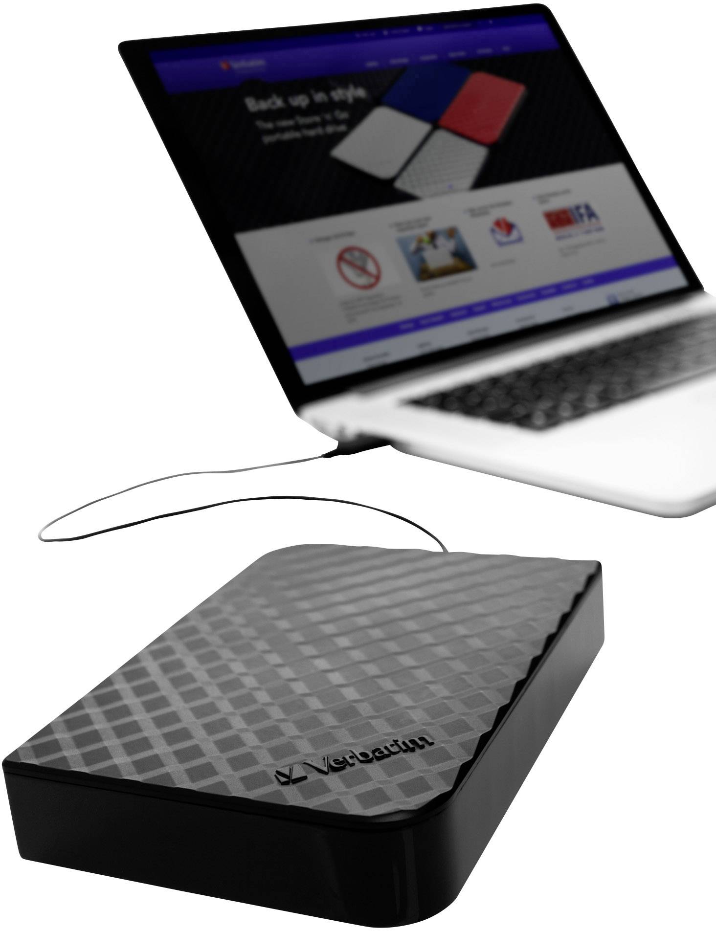 Externe Festplatte von Verbatim mit Laptop im Hintergrund. Festplatte hat ein schwarzes, strukturiertes Gehäuse.
